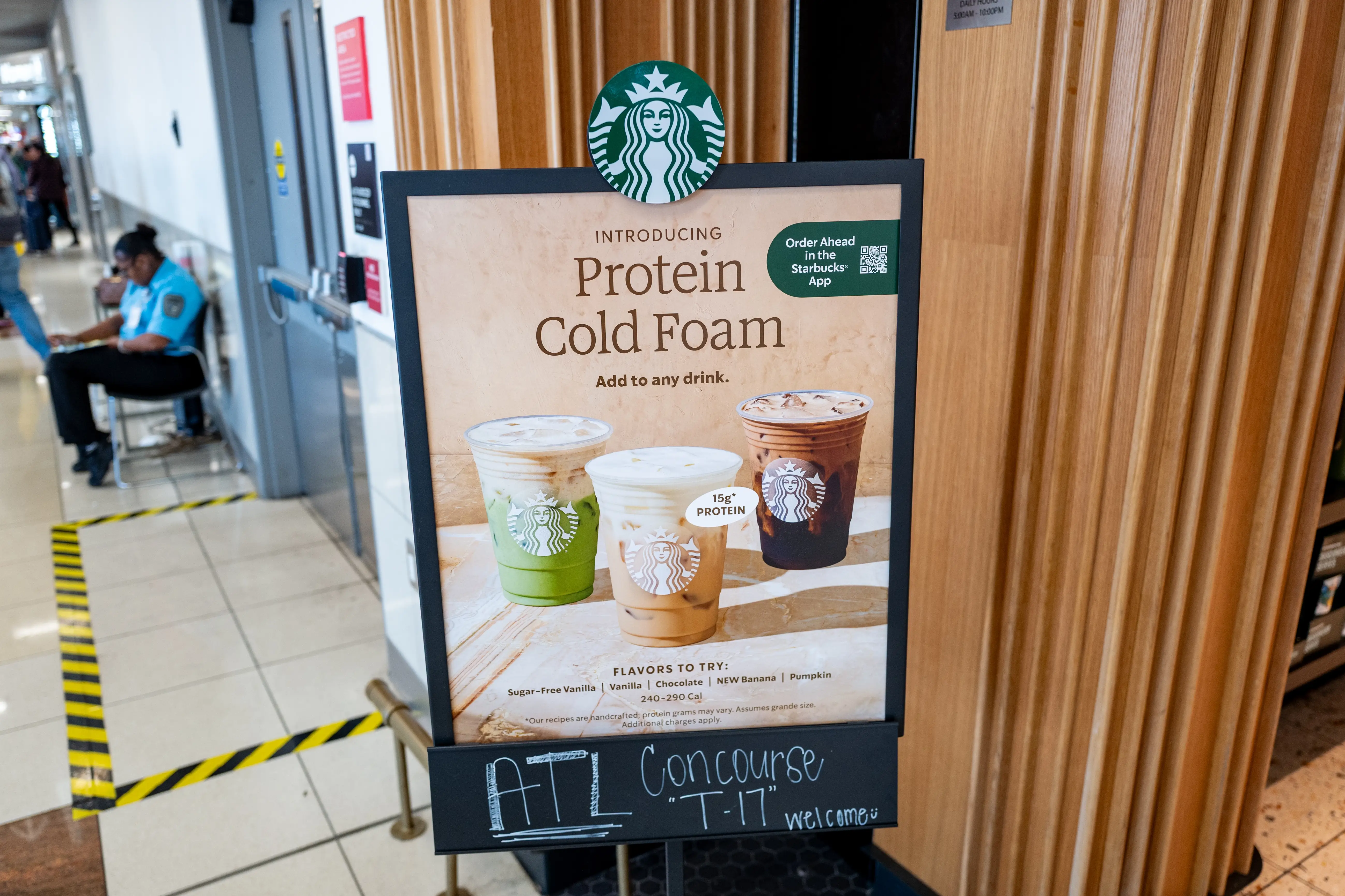 A sign promoting Starbucks' protein cold foam stands outside one of the chain's locations at Atlanta's airport.