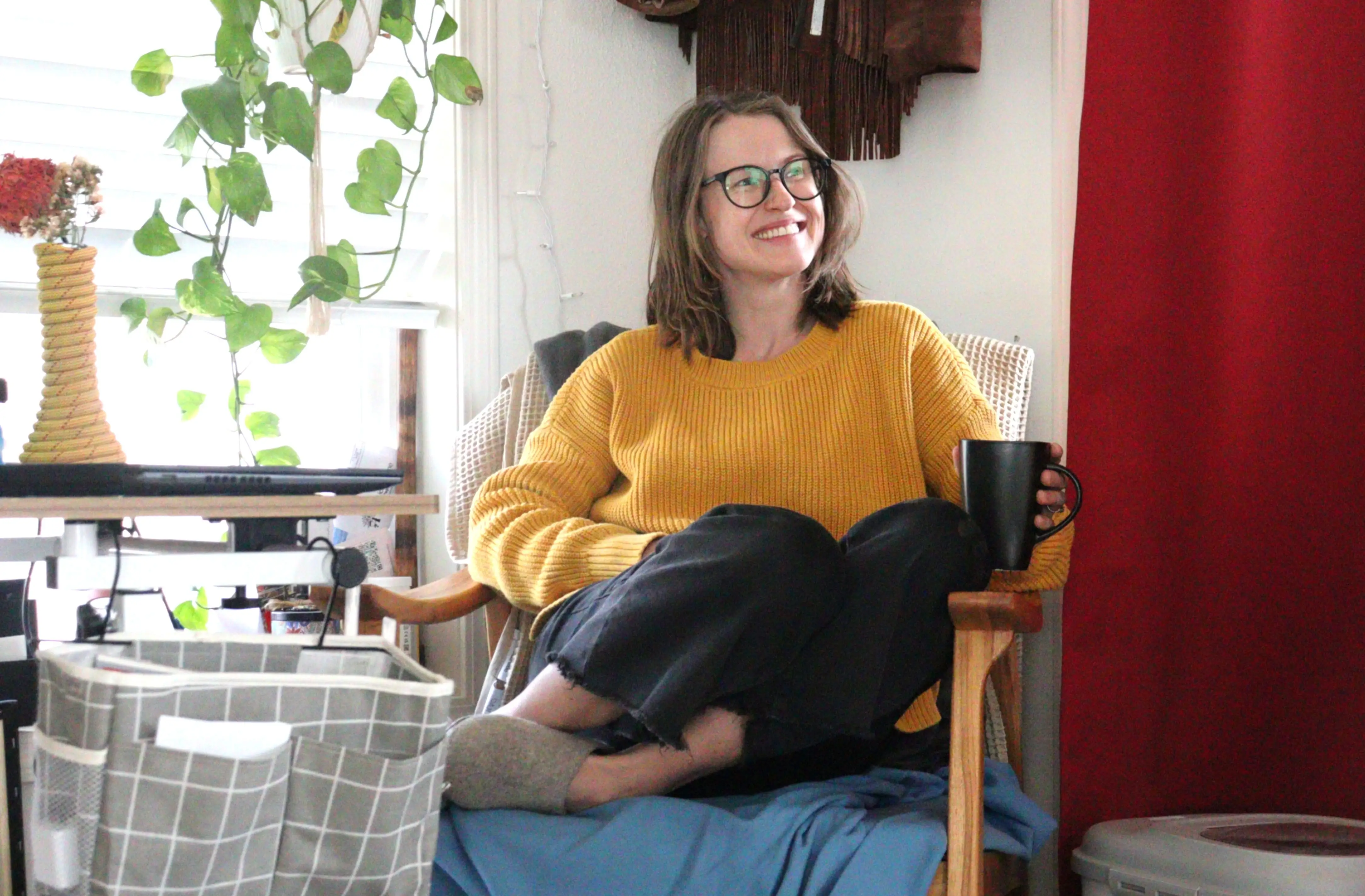 Author Amber McDaniel sitting in chair in tiny. home with cup of coffee, smiling