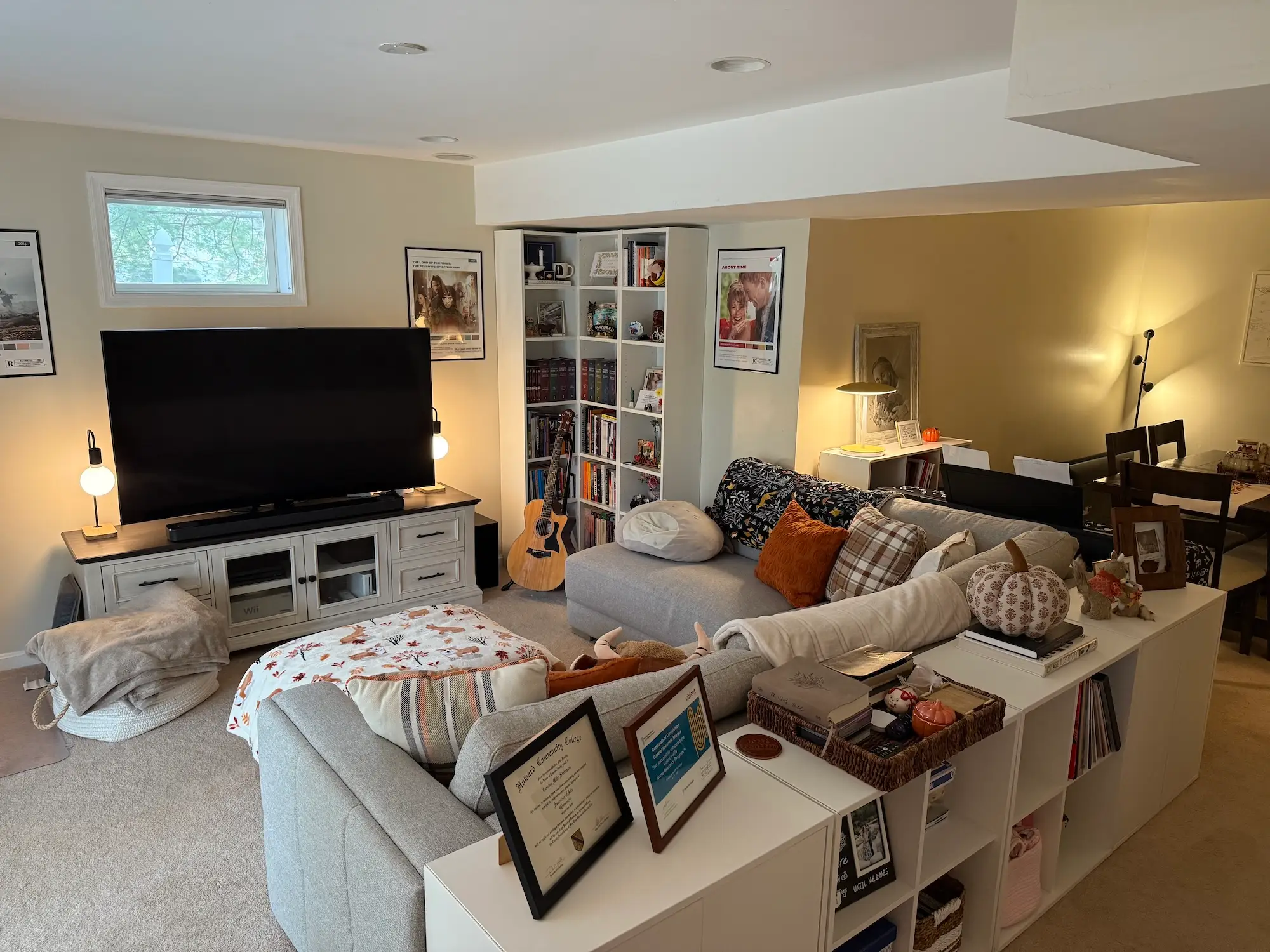 A living area with a sectional couch, TV, and shelving.