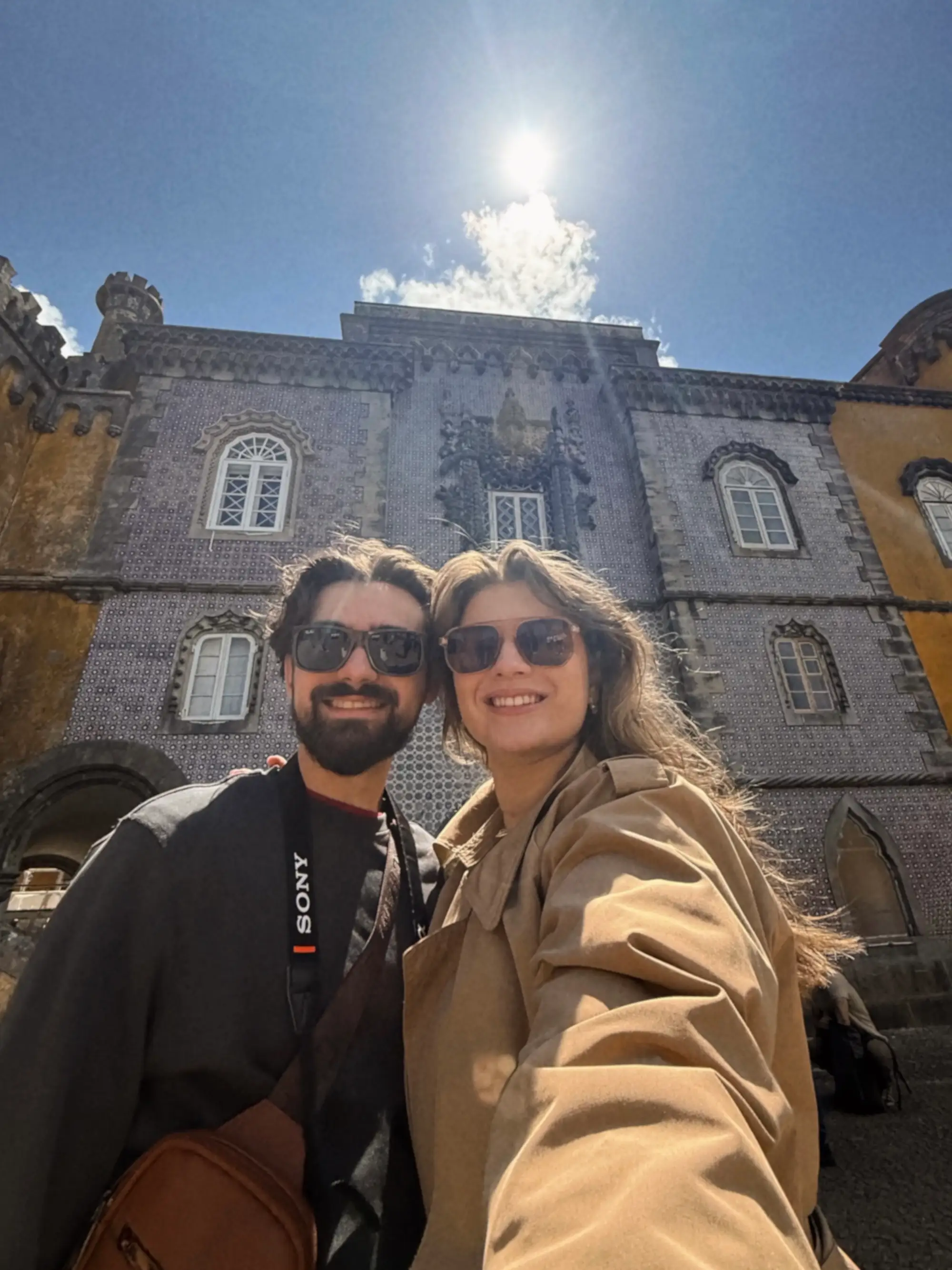 A selfie of a couple in front of stone buildings.