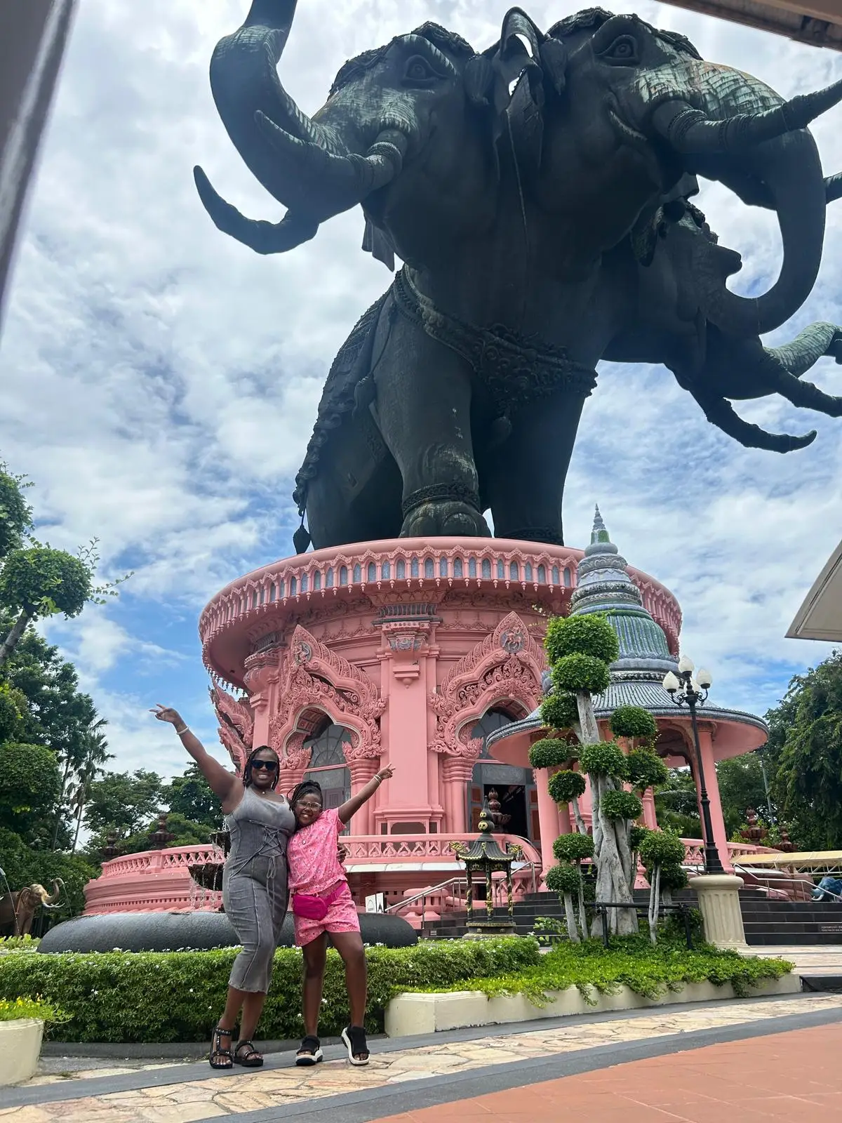 A woman and her daughter posing for a photo with a statue.