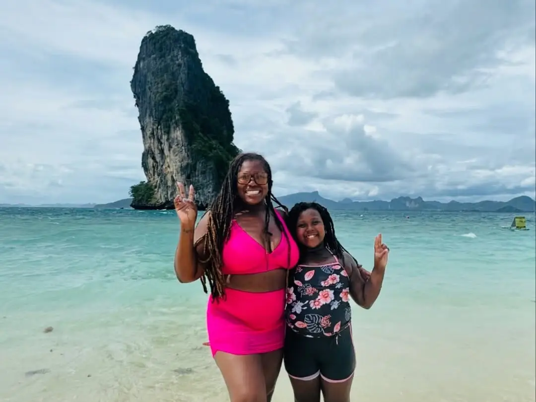 A woman and her daughter posing in the water at the beach.