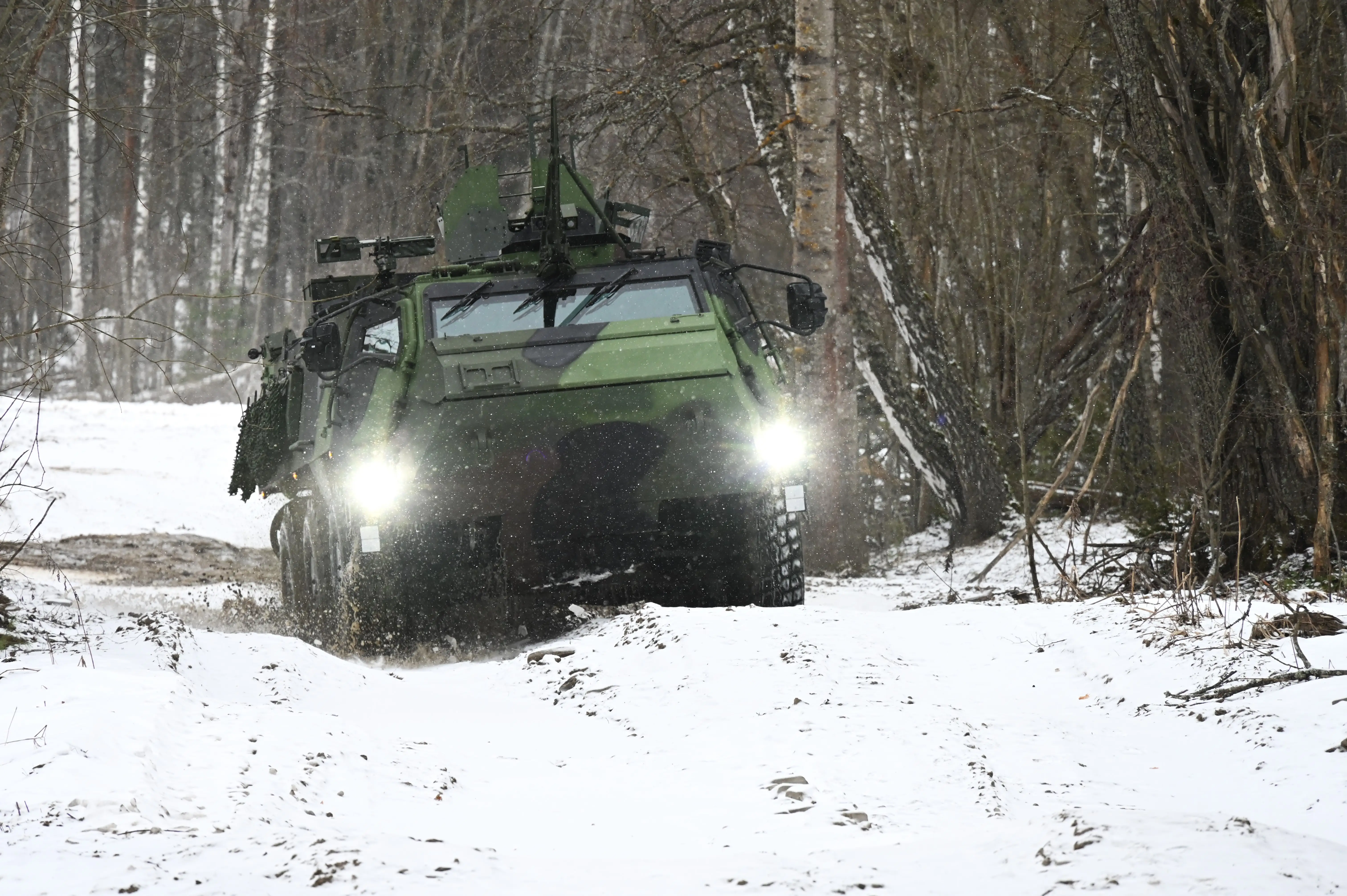 A Patria CAVS 6x6 rolls through mud in the snow.