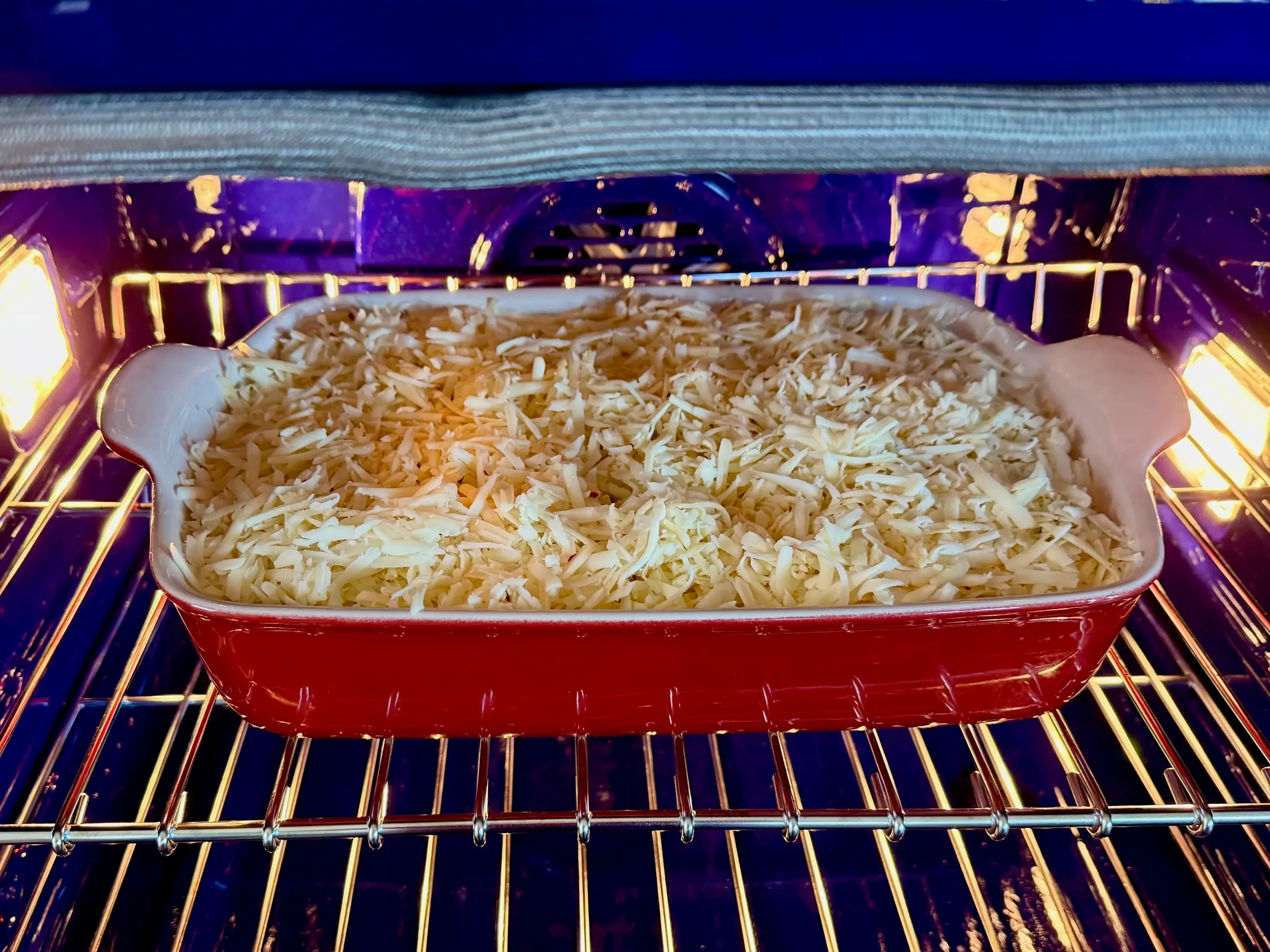The casserole dish topped with cheese sitting in the oven.