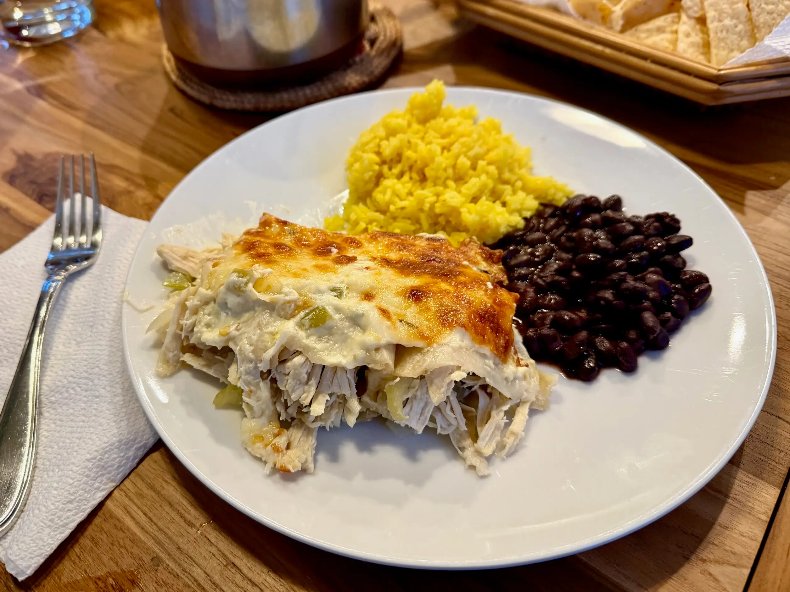 Plated enchilada with a side of rice and beans.