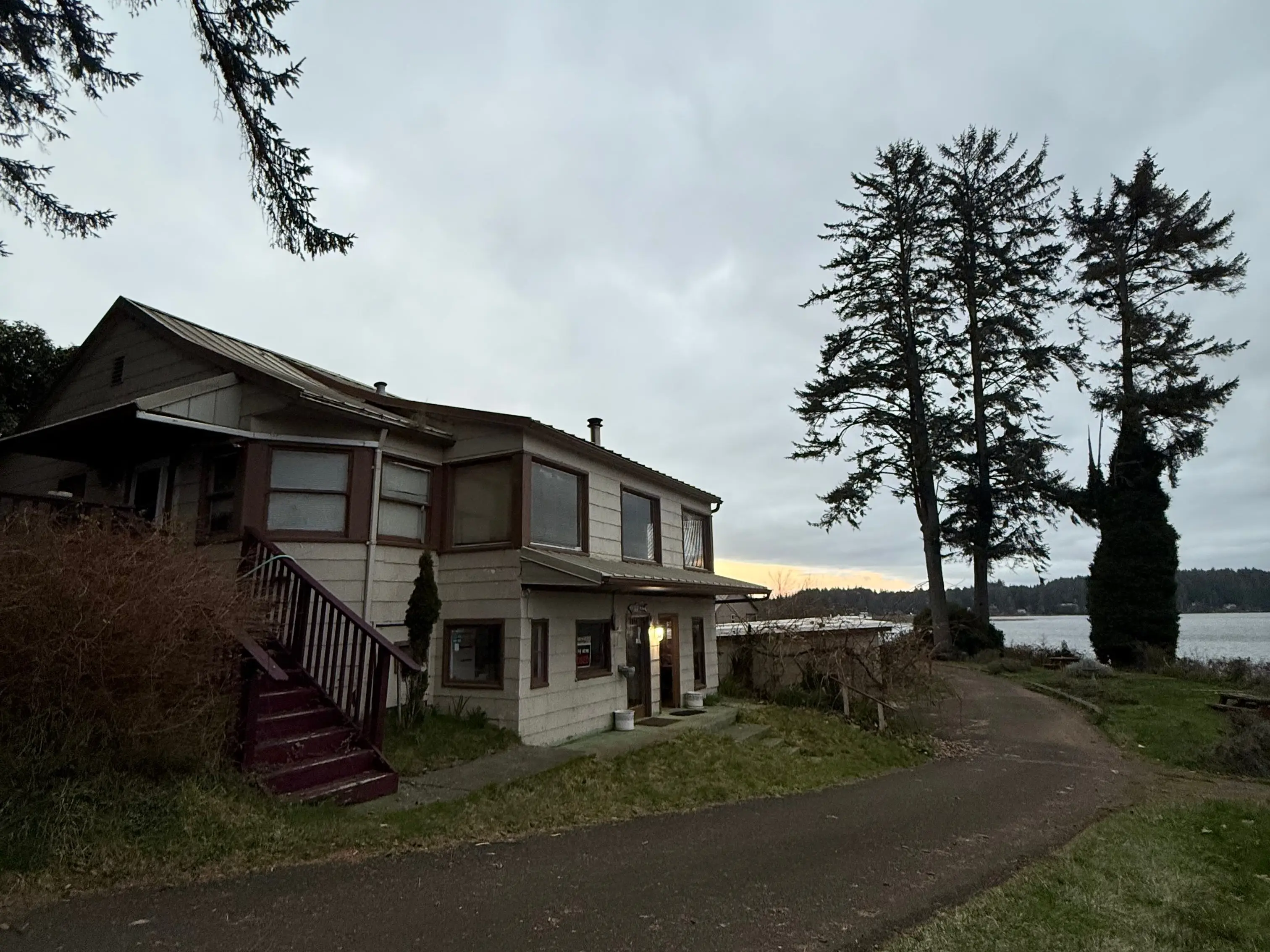 A house on a curved road next to a body of water.