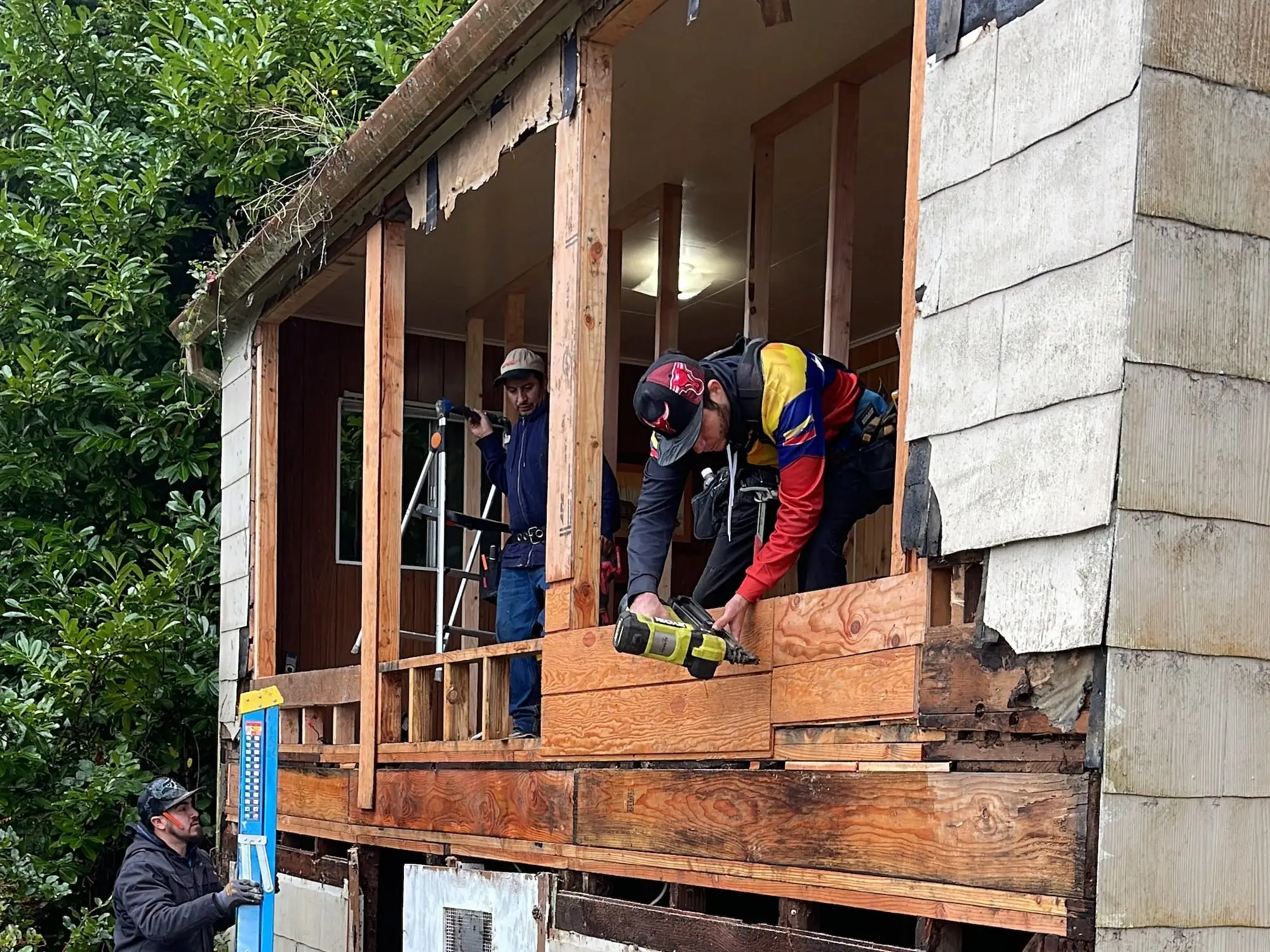 Construction workers work on a building that has a partially open wall.