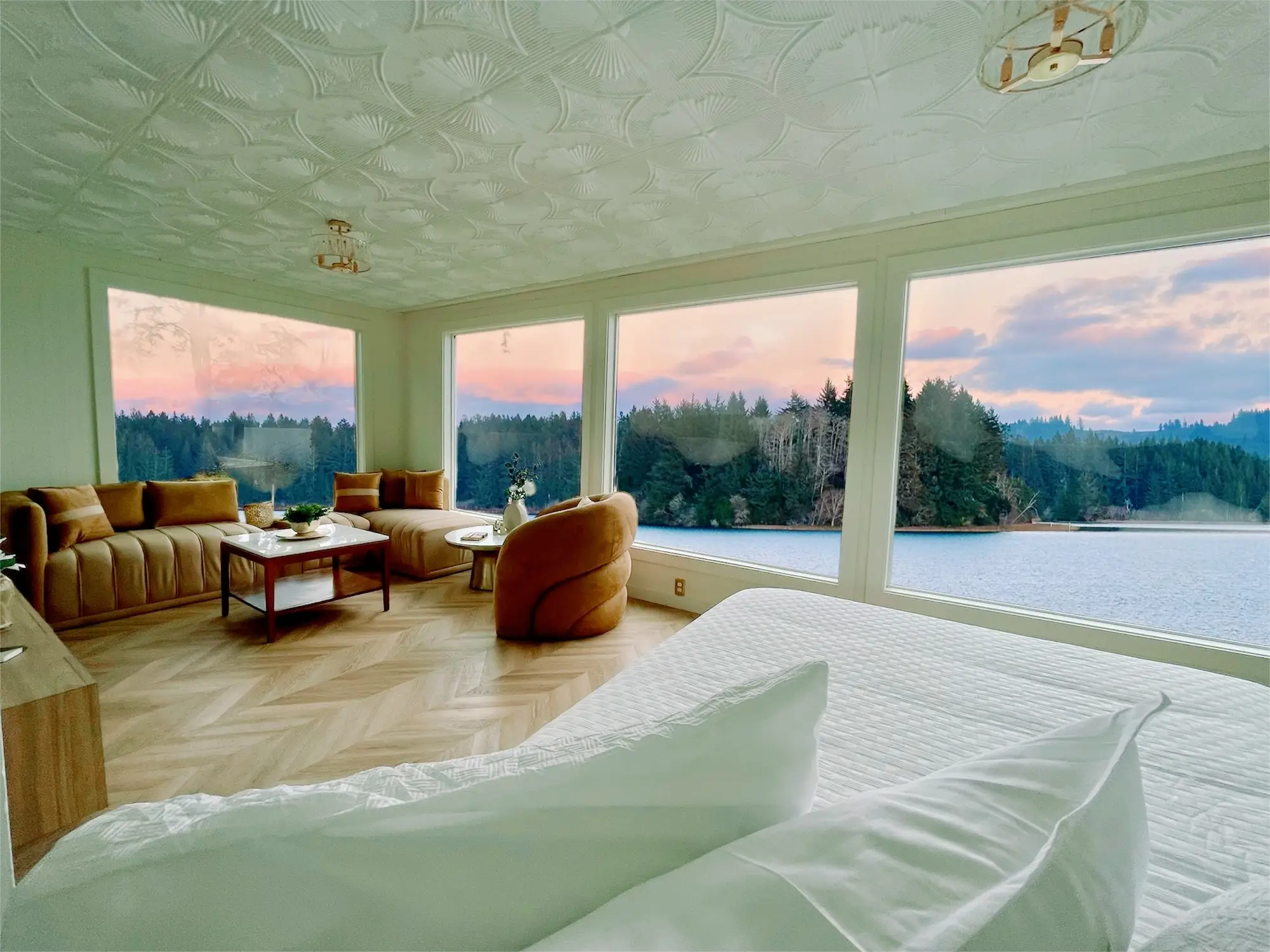 A hotel room with massive windows overlooking a body of water.