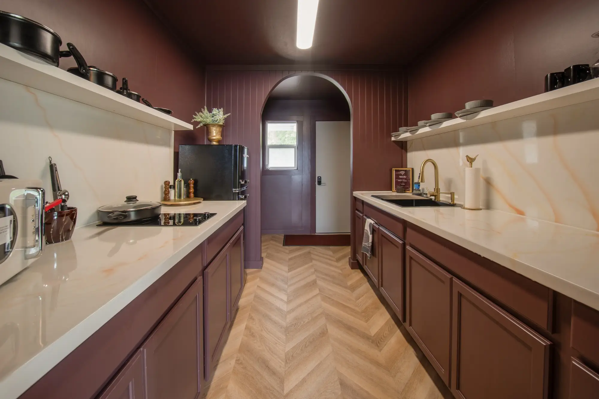 A kitchen with an archway that leads to a doorway. The walls are deep purple.