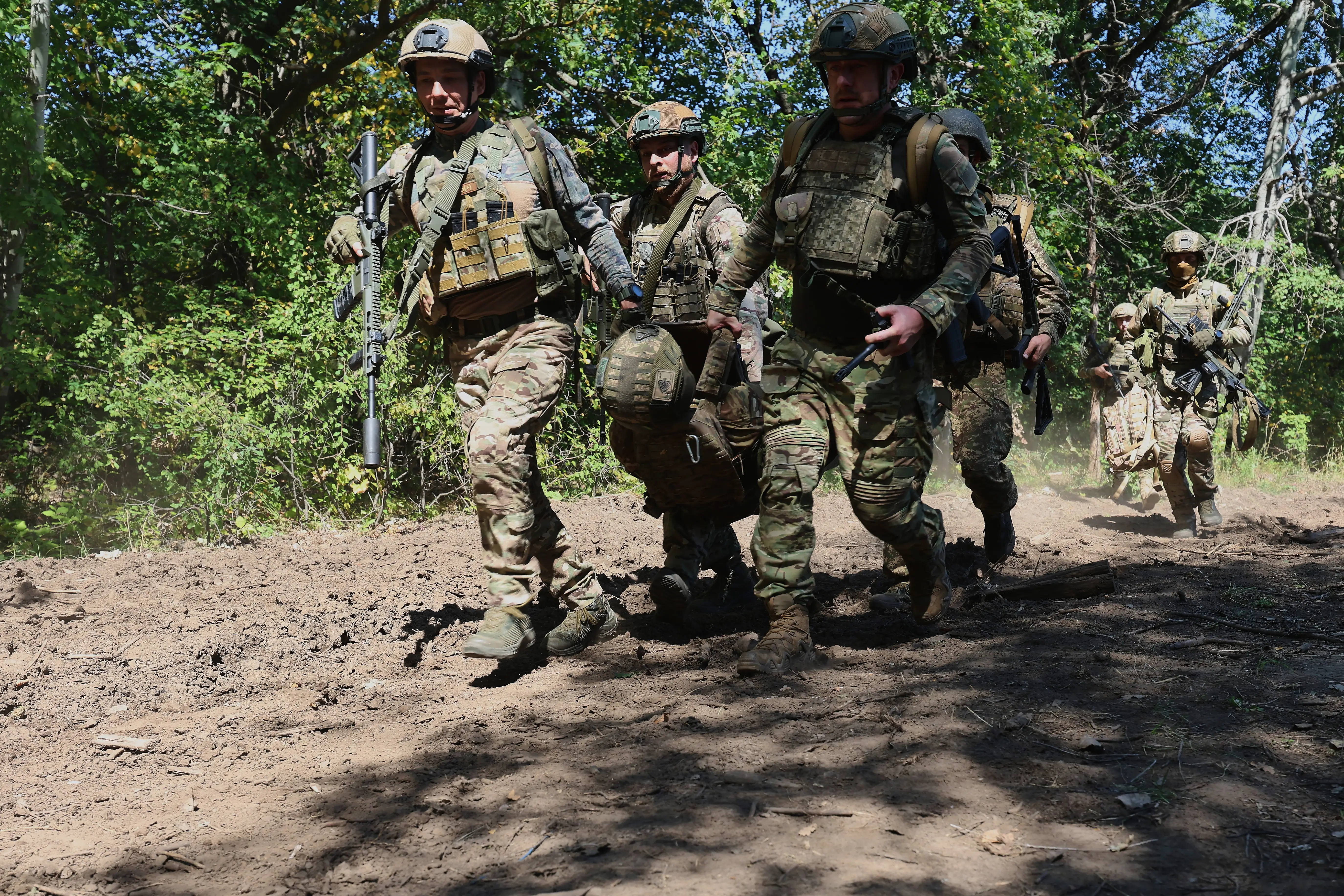 Infantrymen of the operational battalion of the 13th Brigade of the National Guard of Ukraine evacuate a simulated casualty from a danger zone on the battlefield during the airborne training exercise in the Kharkiv region, Ukraine, on August 29, 2023.