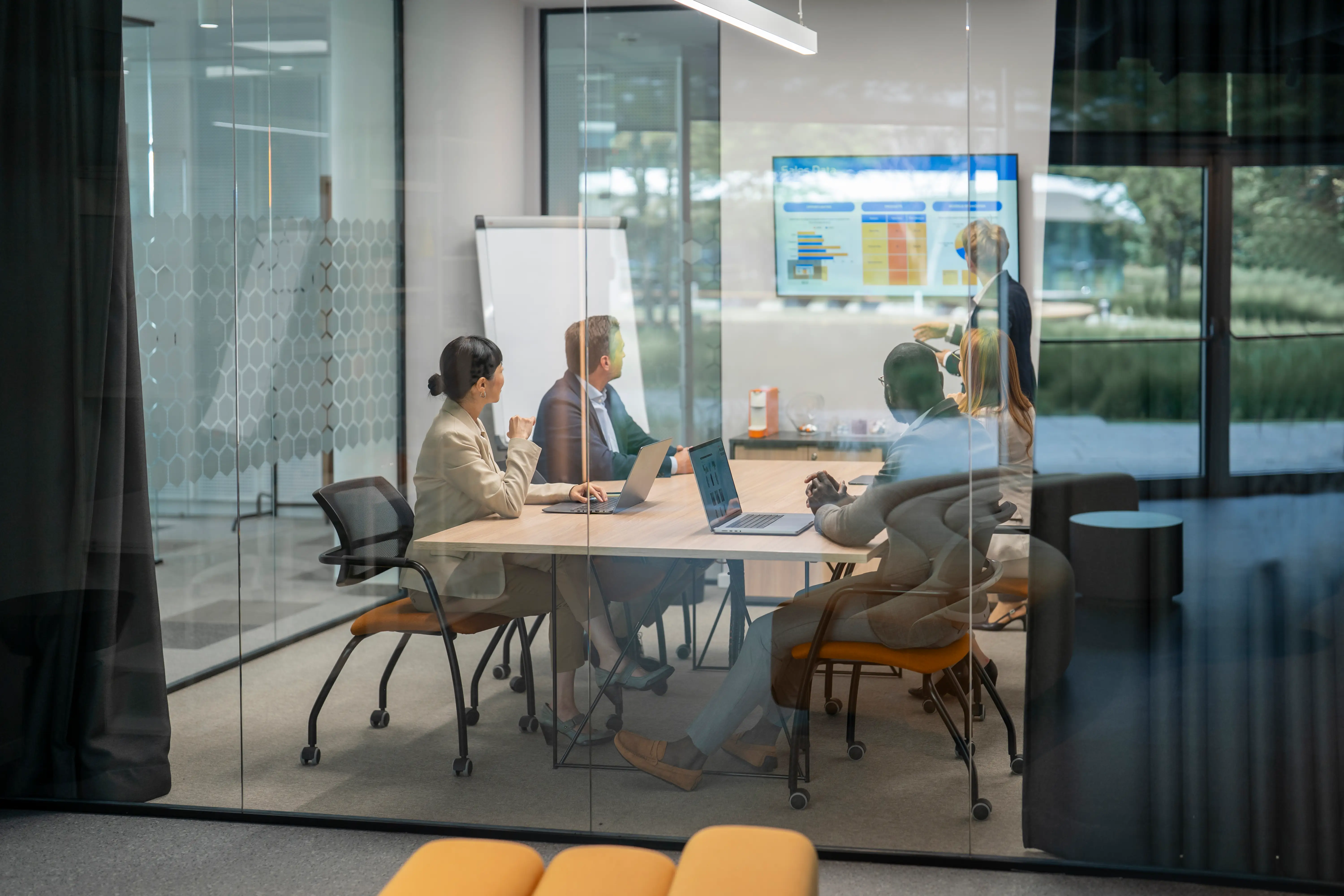 Group of business professionals having a productive meeting, analyzing charts and graphs on a monitor.