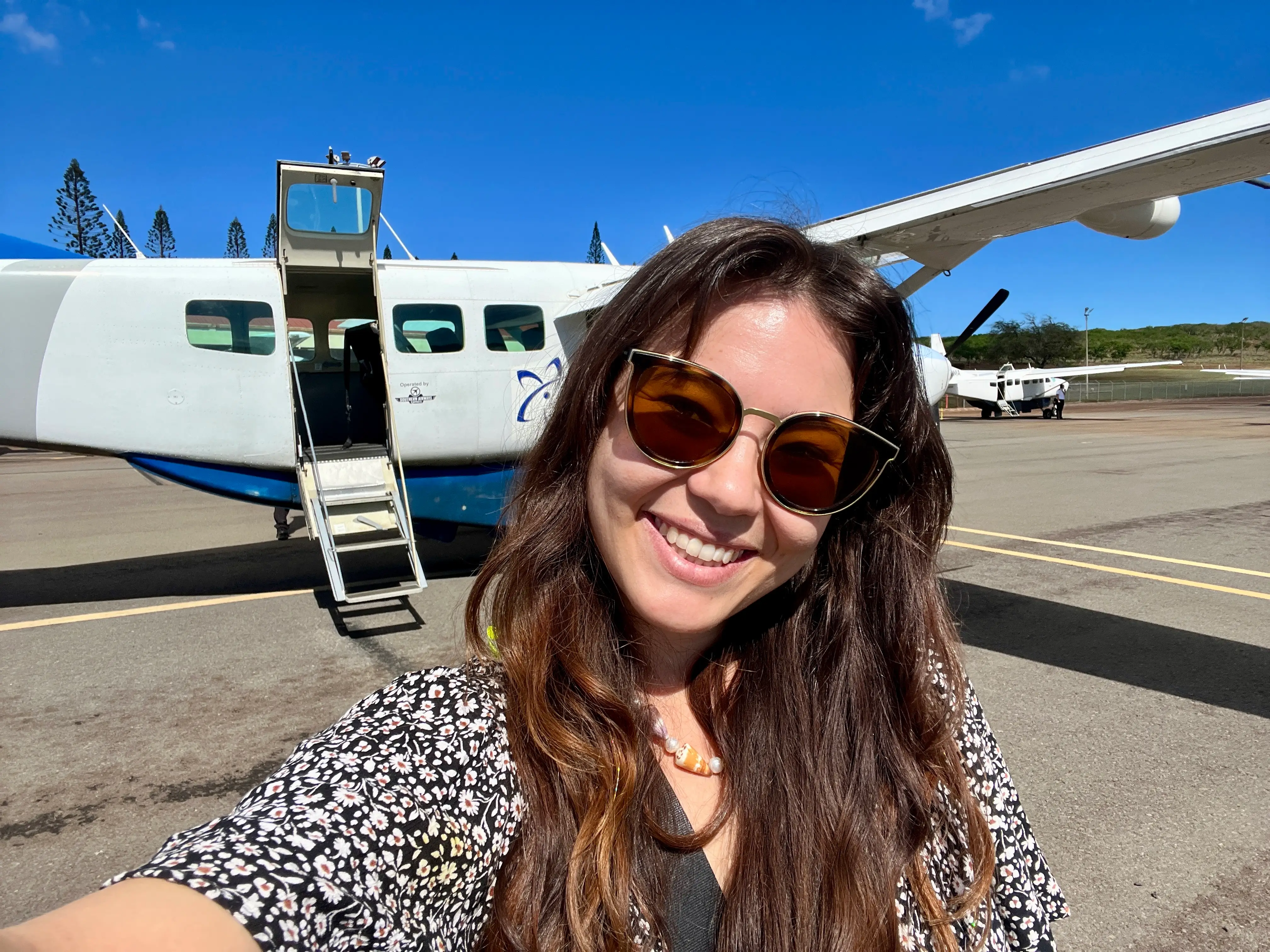 Author Ashley Probst smiling in front of small plane