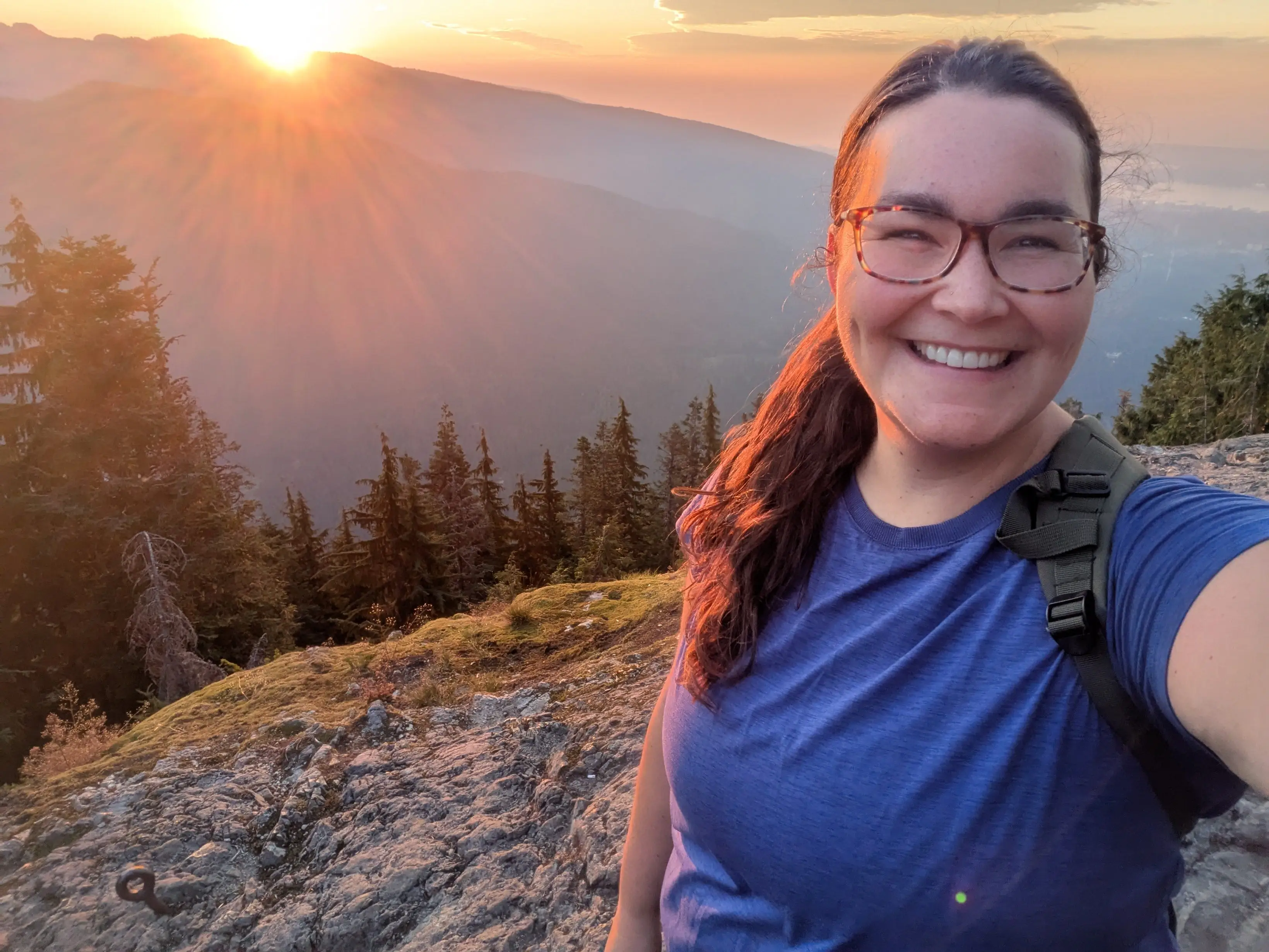 The author smiling with the sun in the background on the Dog Mountain Trail at Mt. Seymour.