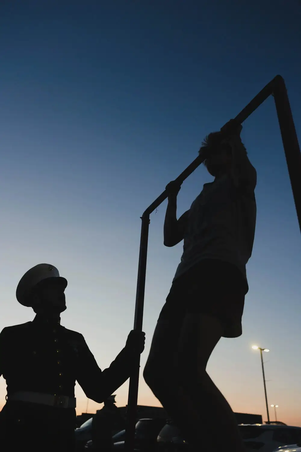 U.S. Marine observes a game attendee attempt the pull-up challenge.