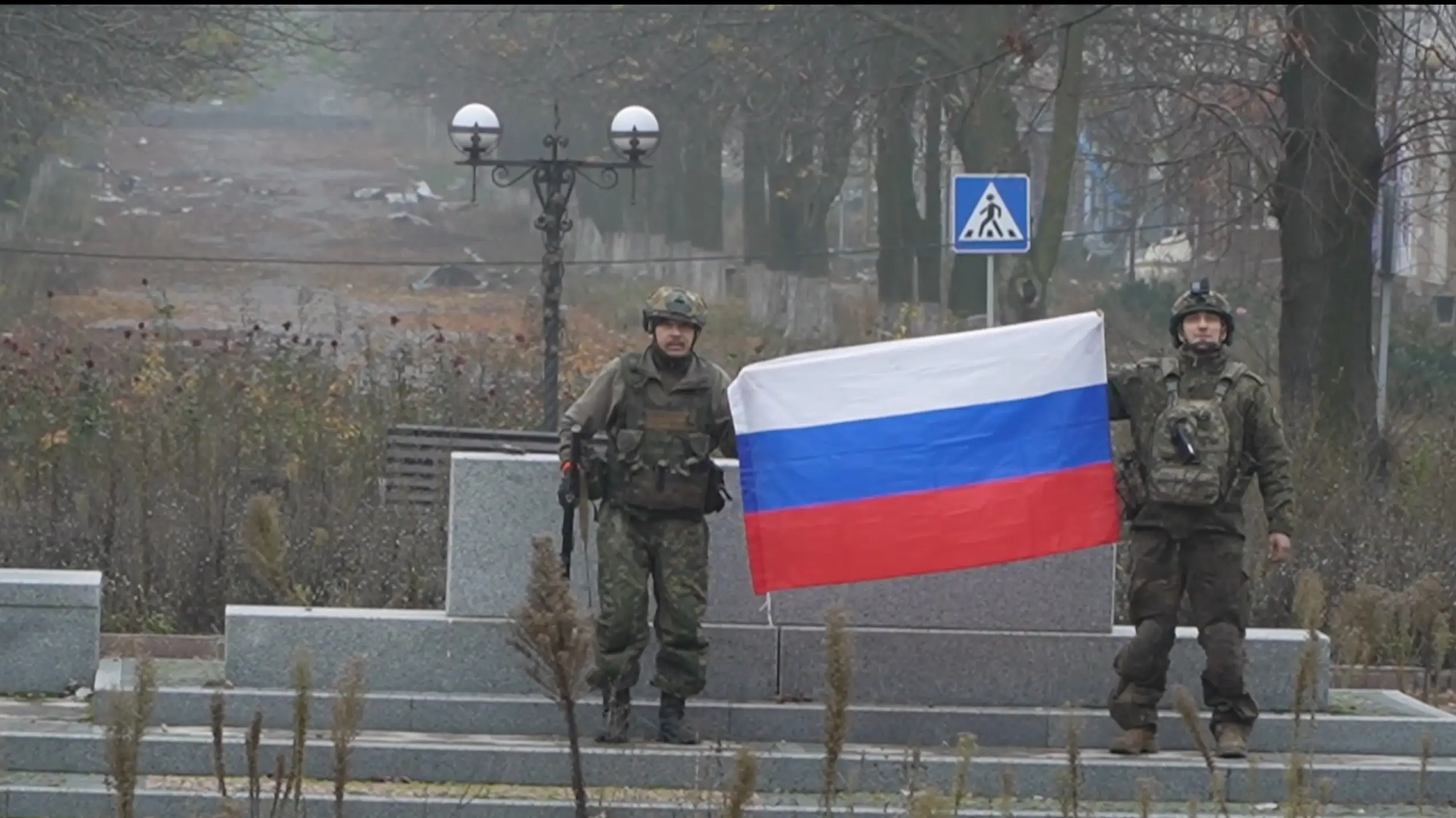 A screen grab from a video shows Russian soldiers holding up the Russian flag in an urban area.
