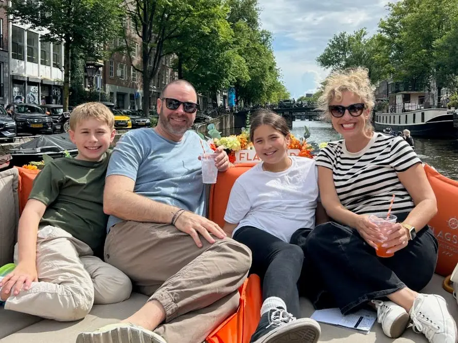 Author Alesandra Dubin, her kids, husband smiling on canal boat in Amsterdam