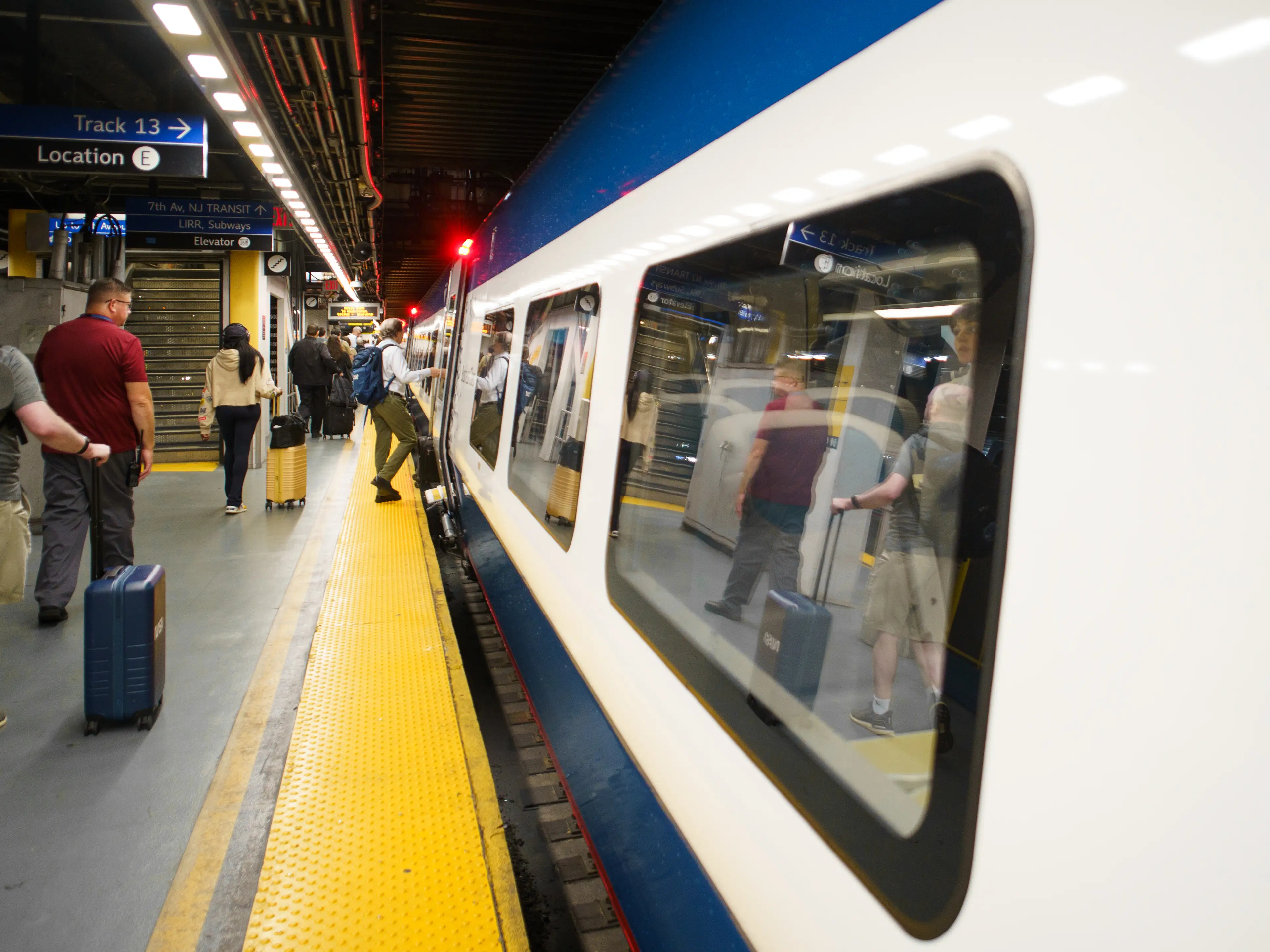 People board a train on the right in an underground platform