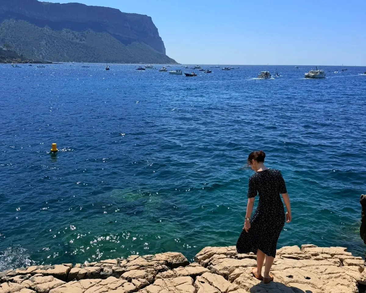 Woman standing next to blue water at Côte d'Azur