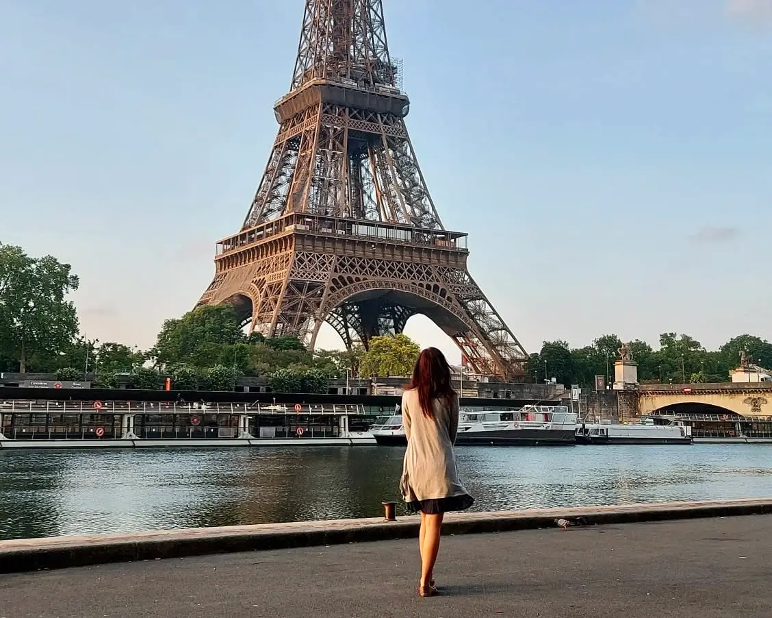 Woman standing in front of eiffel tower at dawn