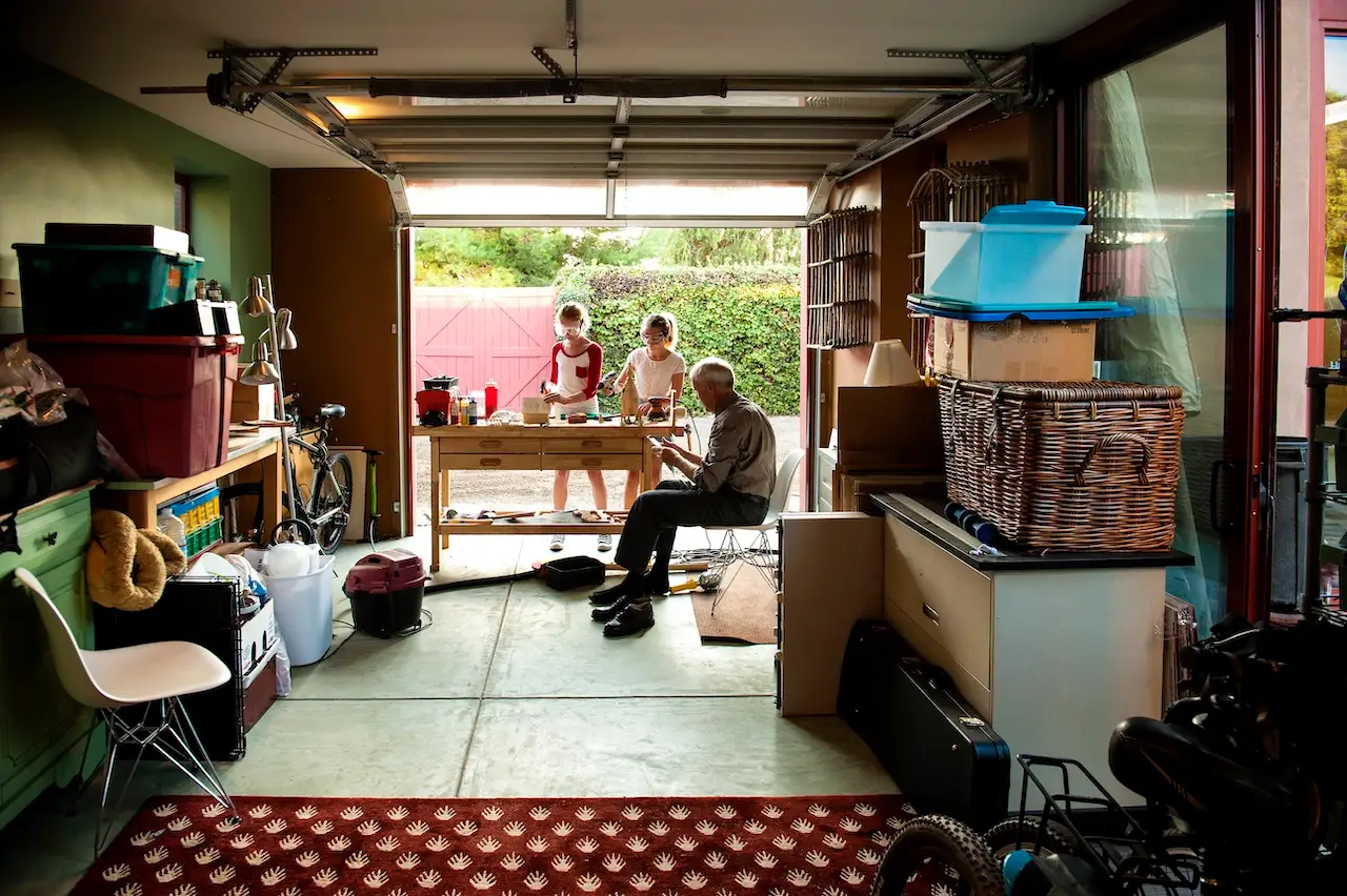 Stock photo of a grandfather watching his granddaughters build a birdhouse in a garage.