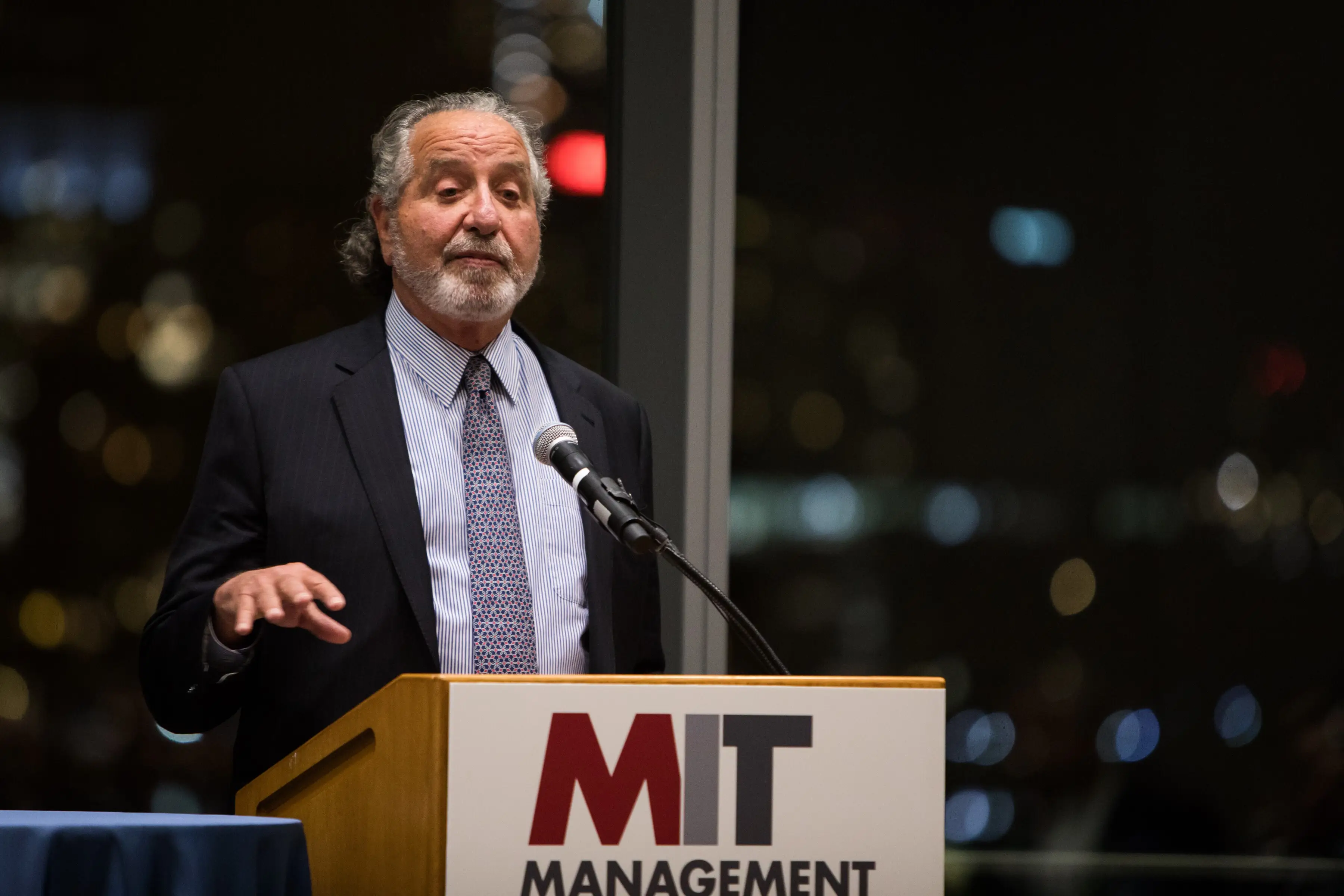 Donald Sussman stands behind a podium in a suit and tie.