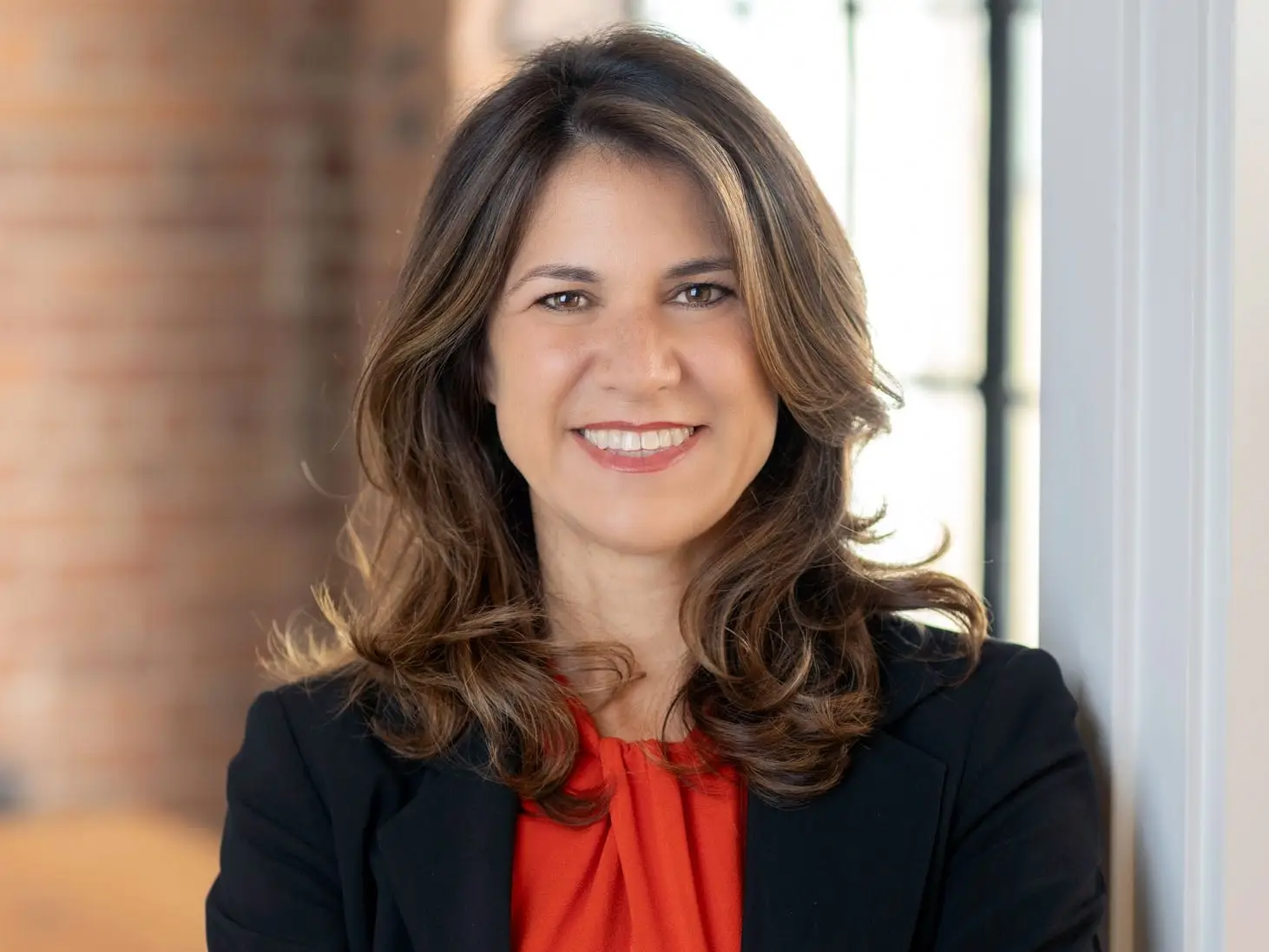 Deborah Carrillo smiles at the camera, standing with her arms folded across her chest.