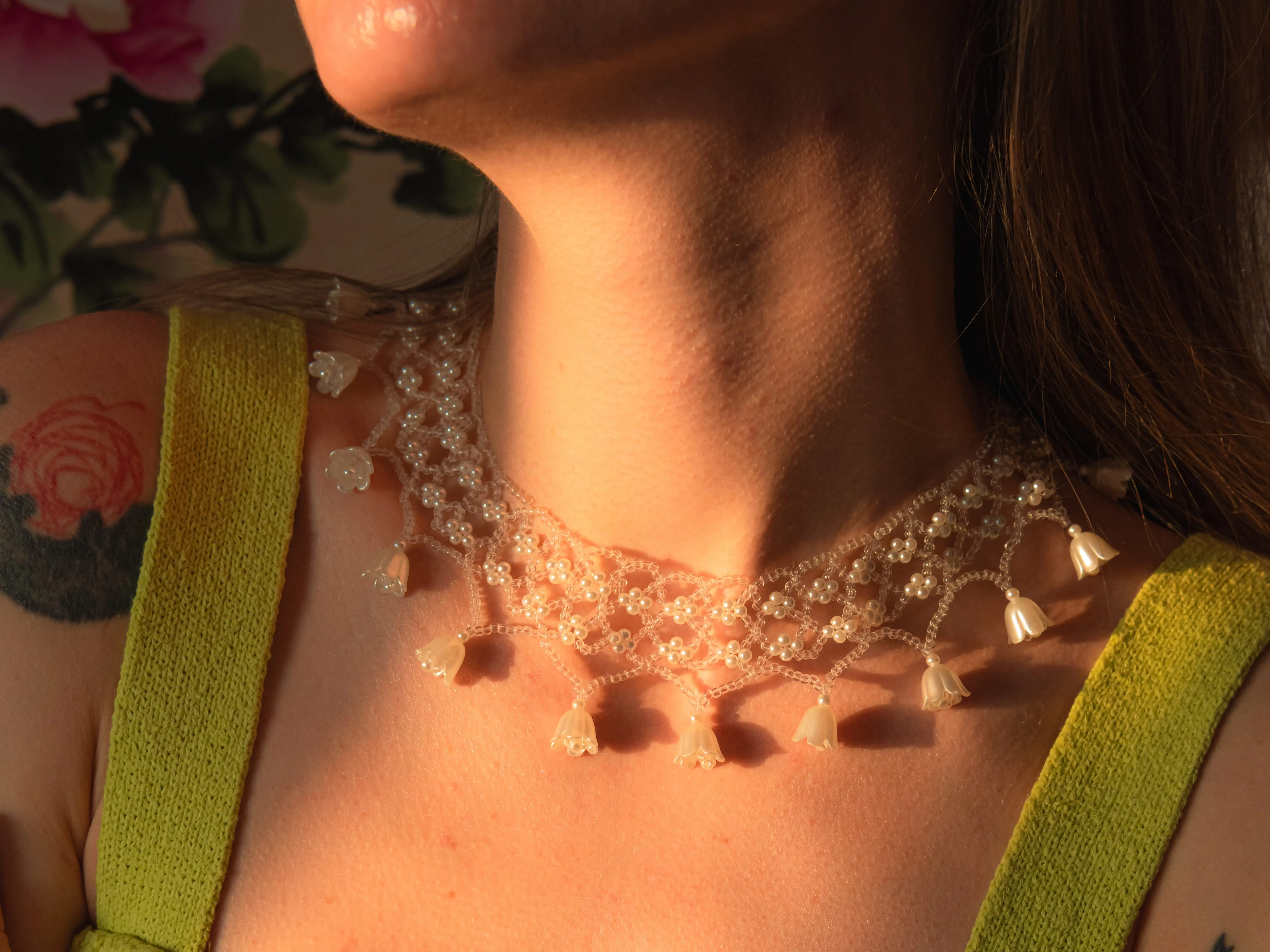 A woman in a green dress with a beaded necklace.