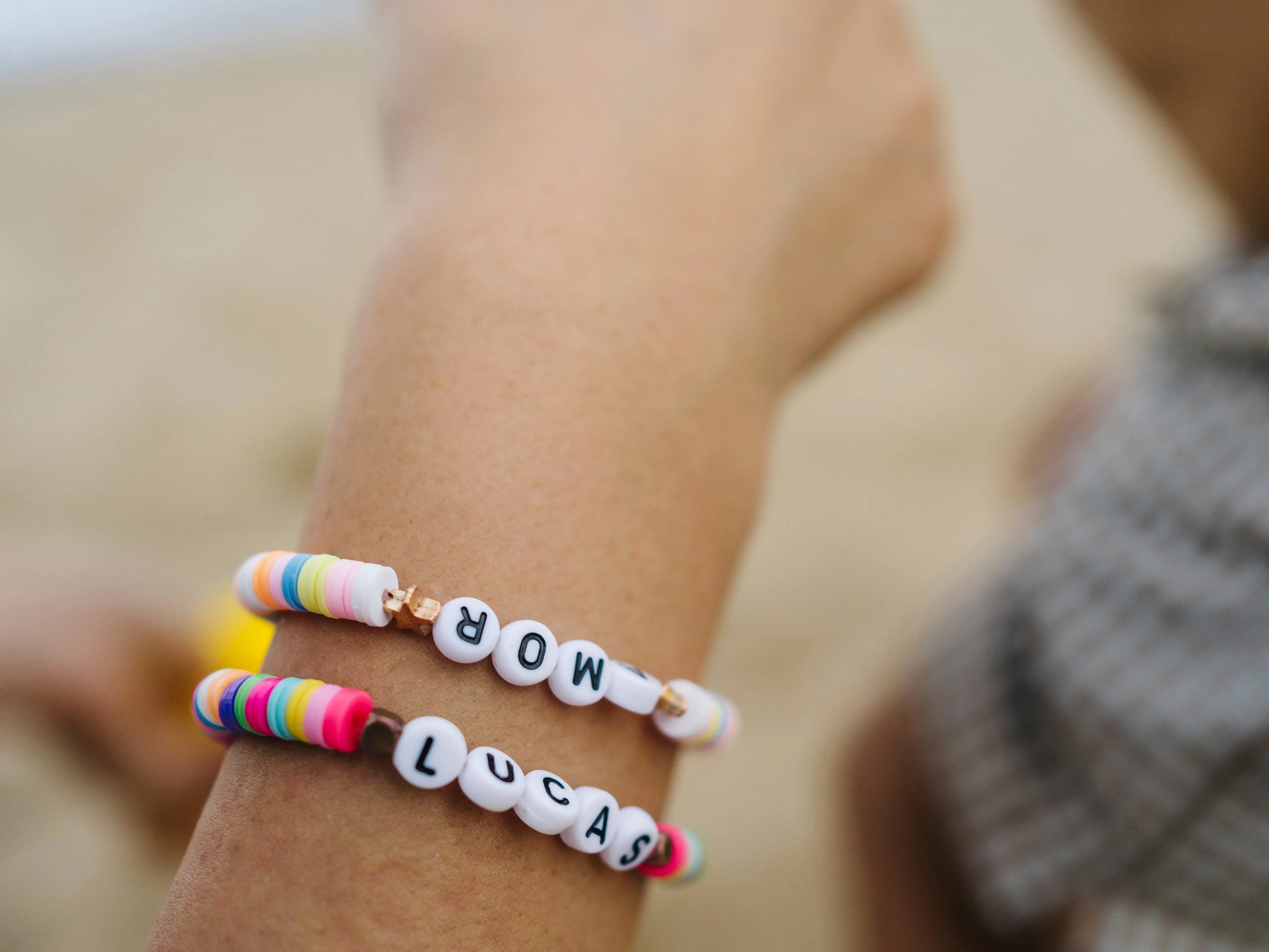 A hand with two friendship bracelets, one reading