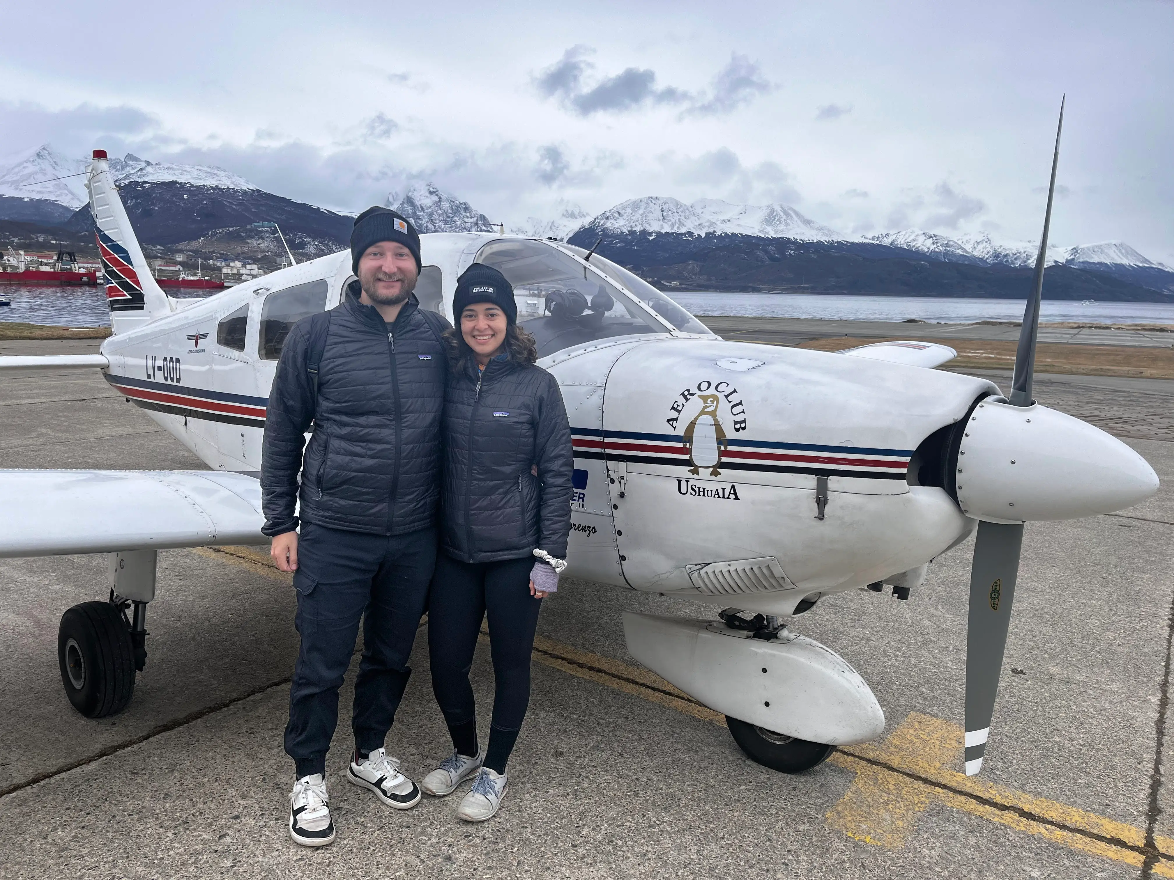 The author and her partner posing in front of a small, private plane.
