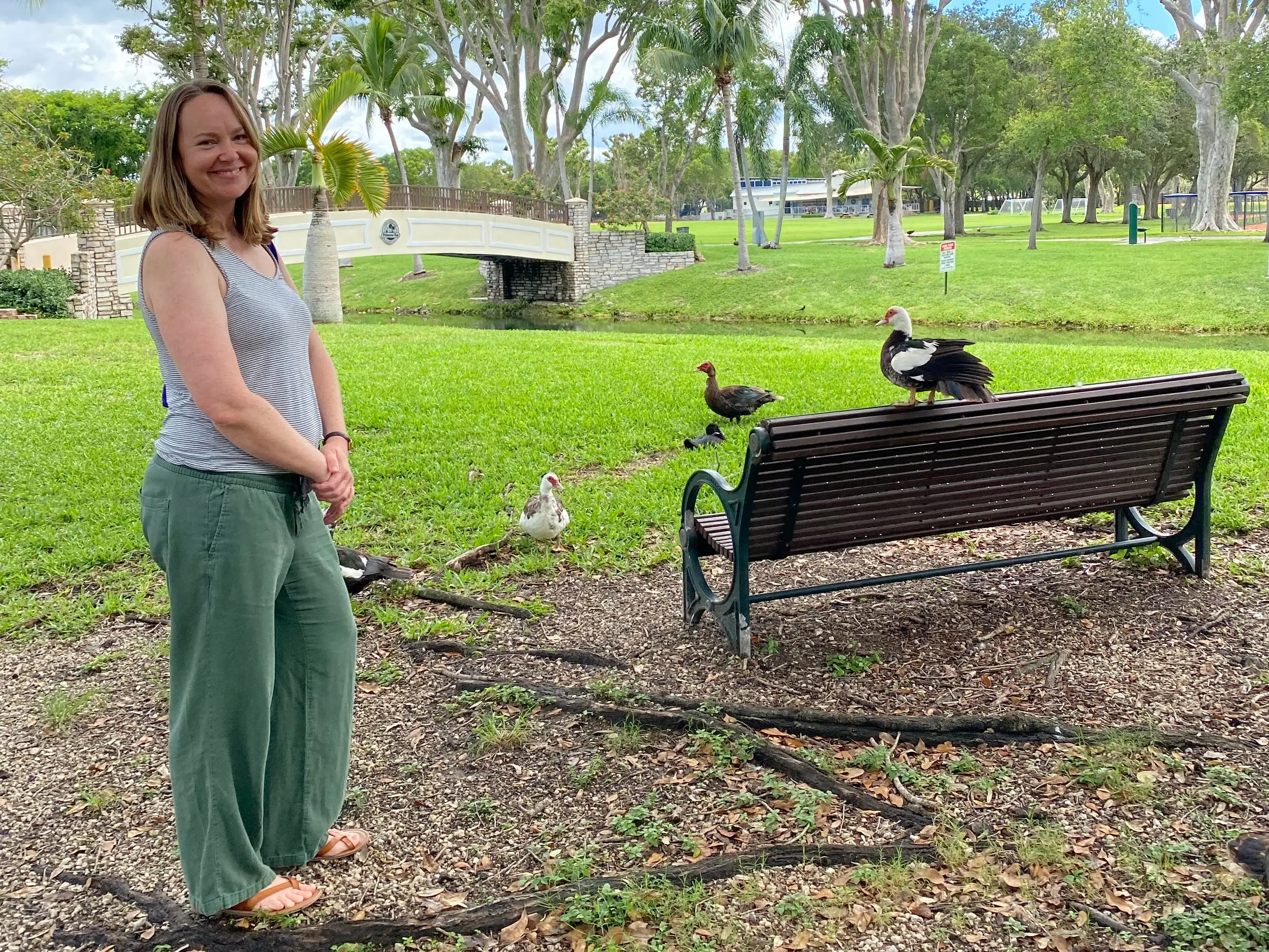 Author Ashley Archambault smiling in Miami with chickens nearby