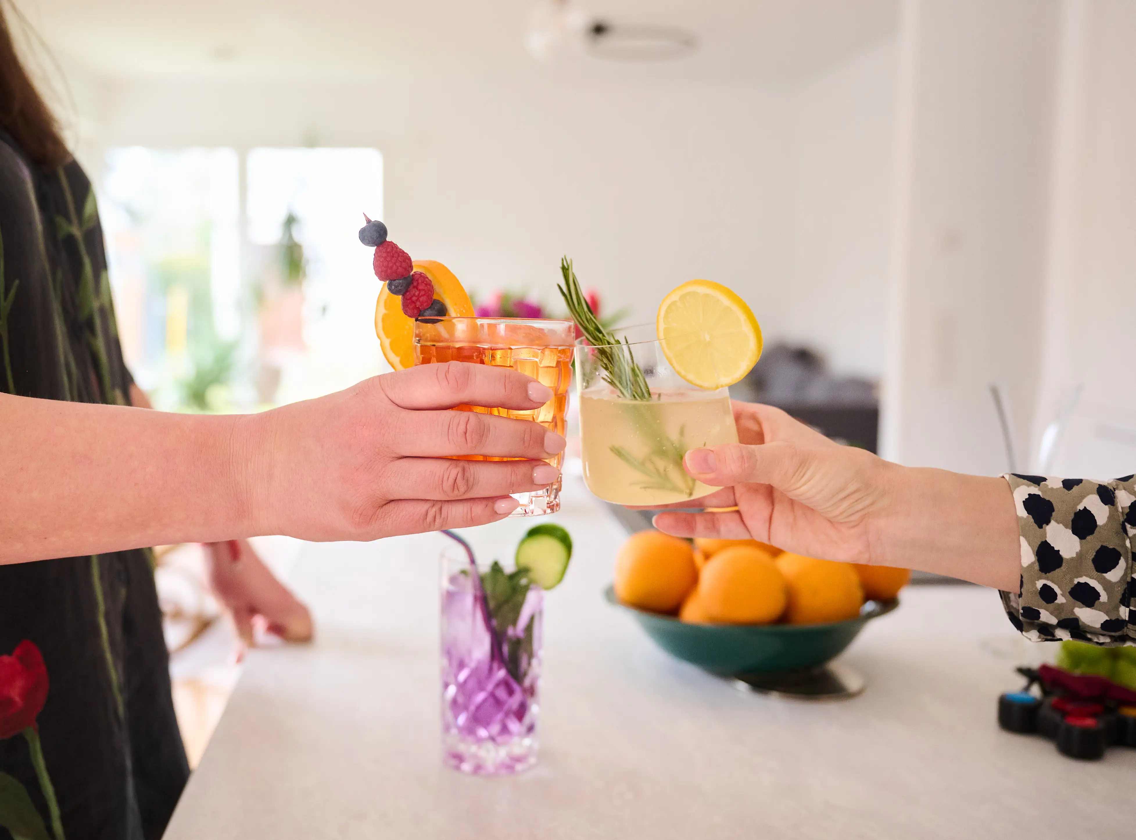Two women clink glasses containing non-alcoholic mocktails.