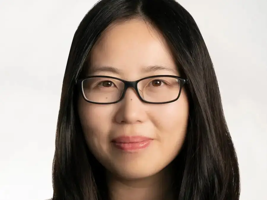 Asian woman wearing glasses smiles.