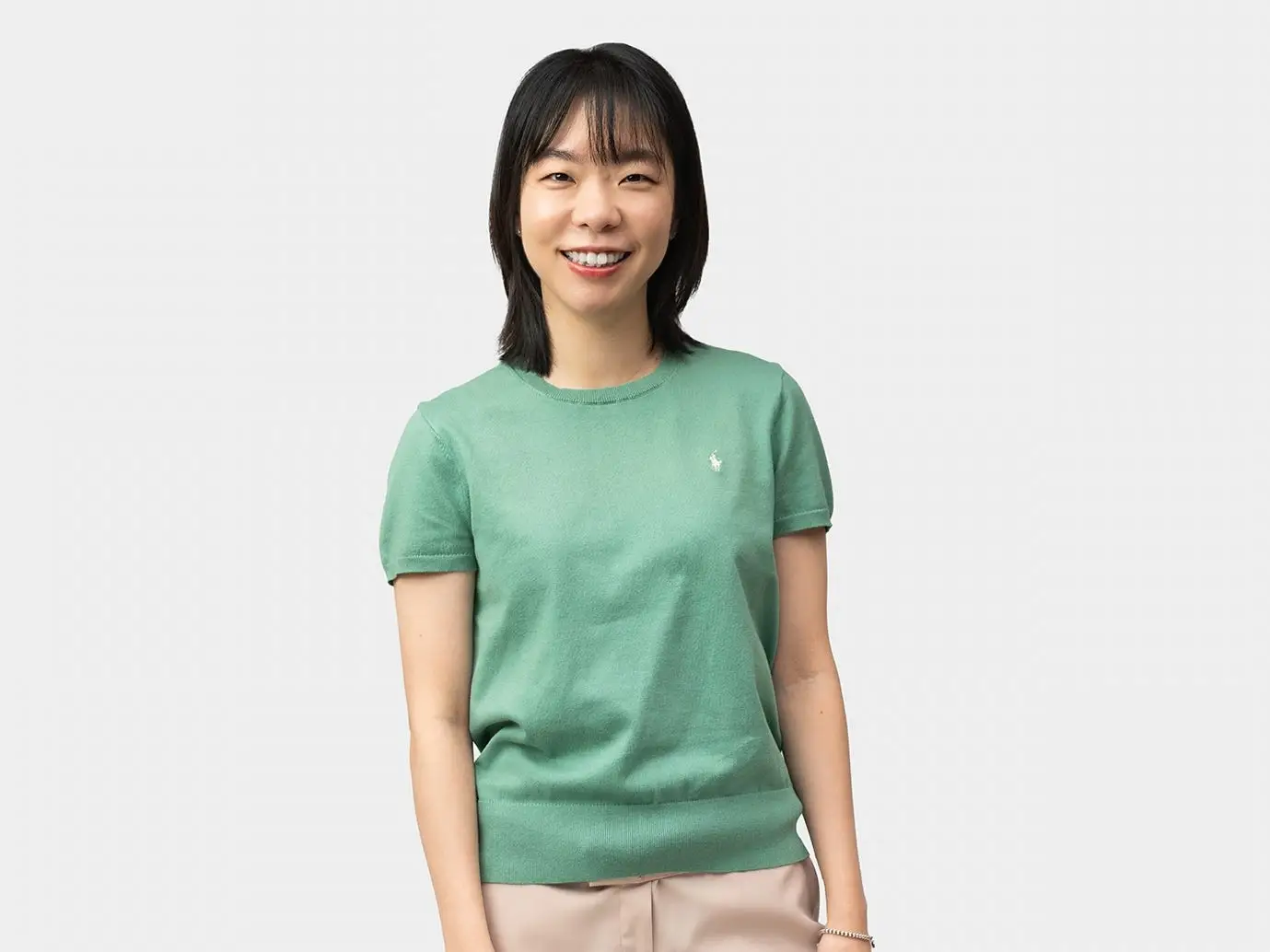 Minjoo Kim smiles for a photo wearing a sea foam green knit shirt.