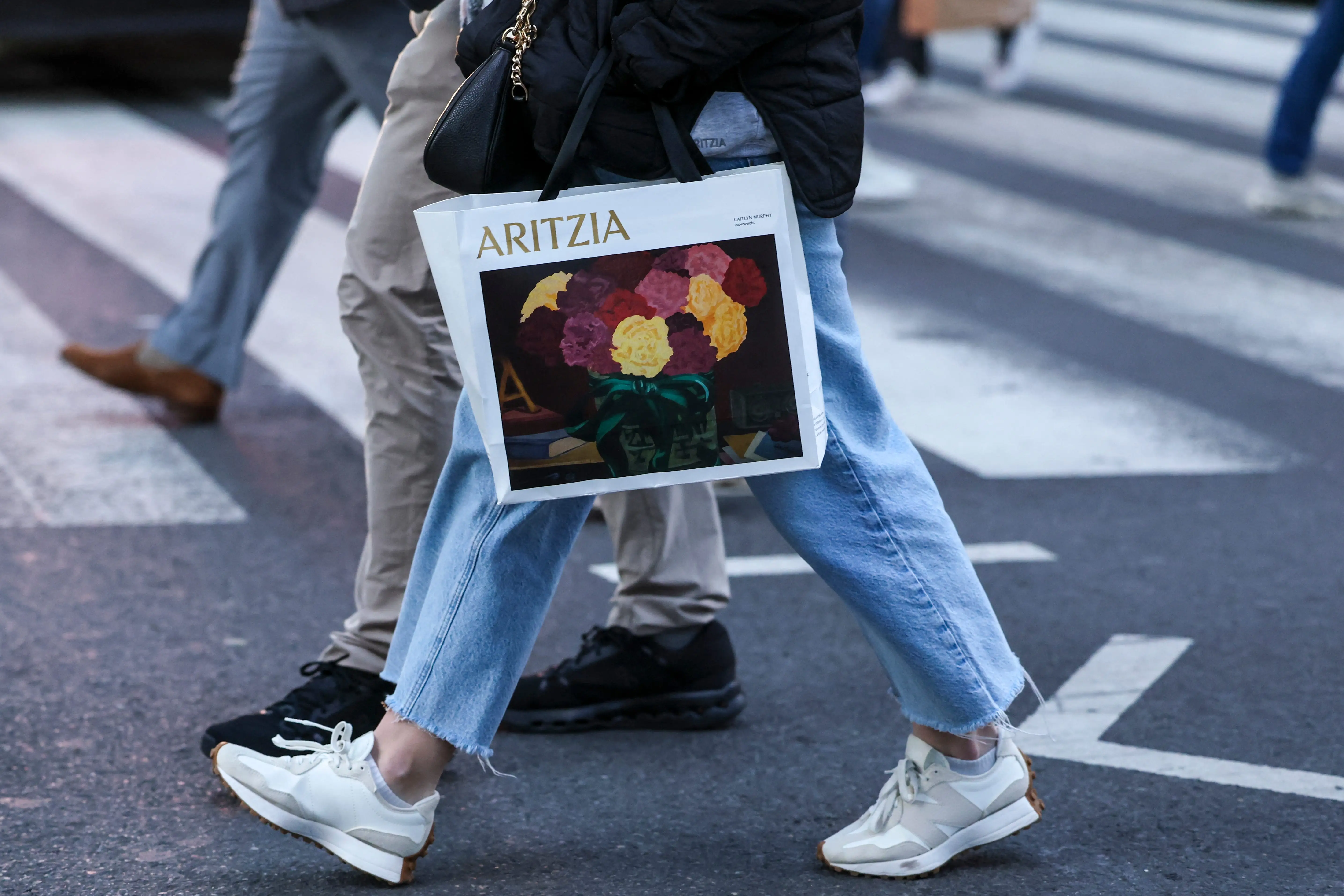 A person holds a shopping bag from retail store Aritzia as people make their way through Herald Square on December 11, 2025 in New York City.