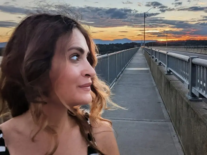 Elana Rabinowitz looks out over a bridge at sunset.