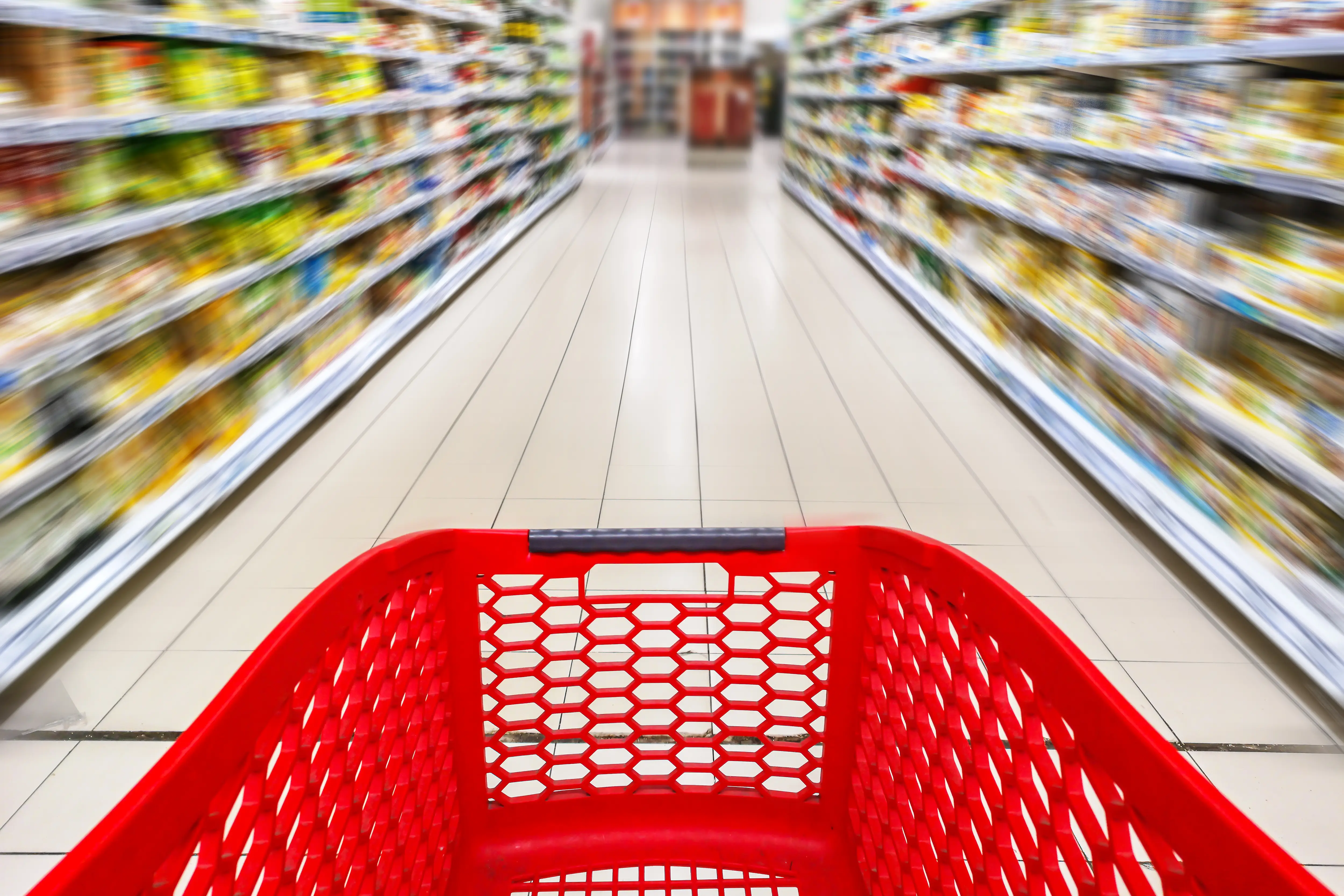 A red car is being pushed down a grocery aisle.