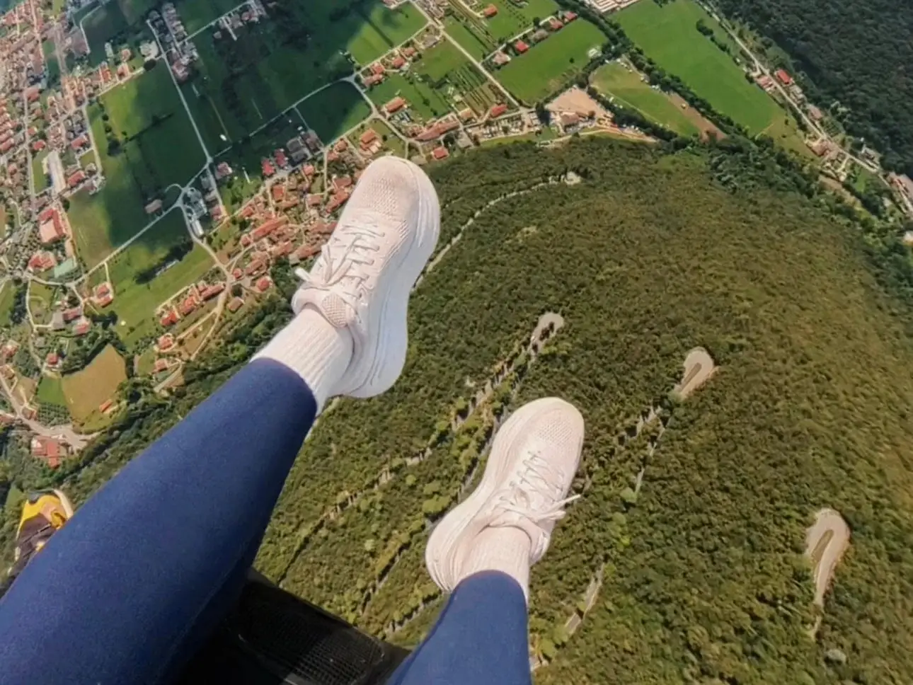 A pair of white shoes dangles out of a plane.