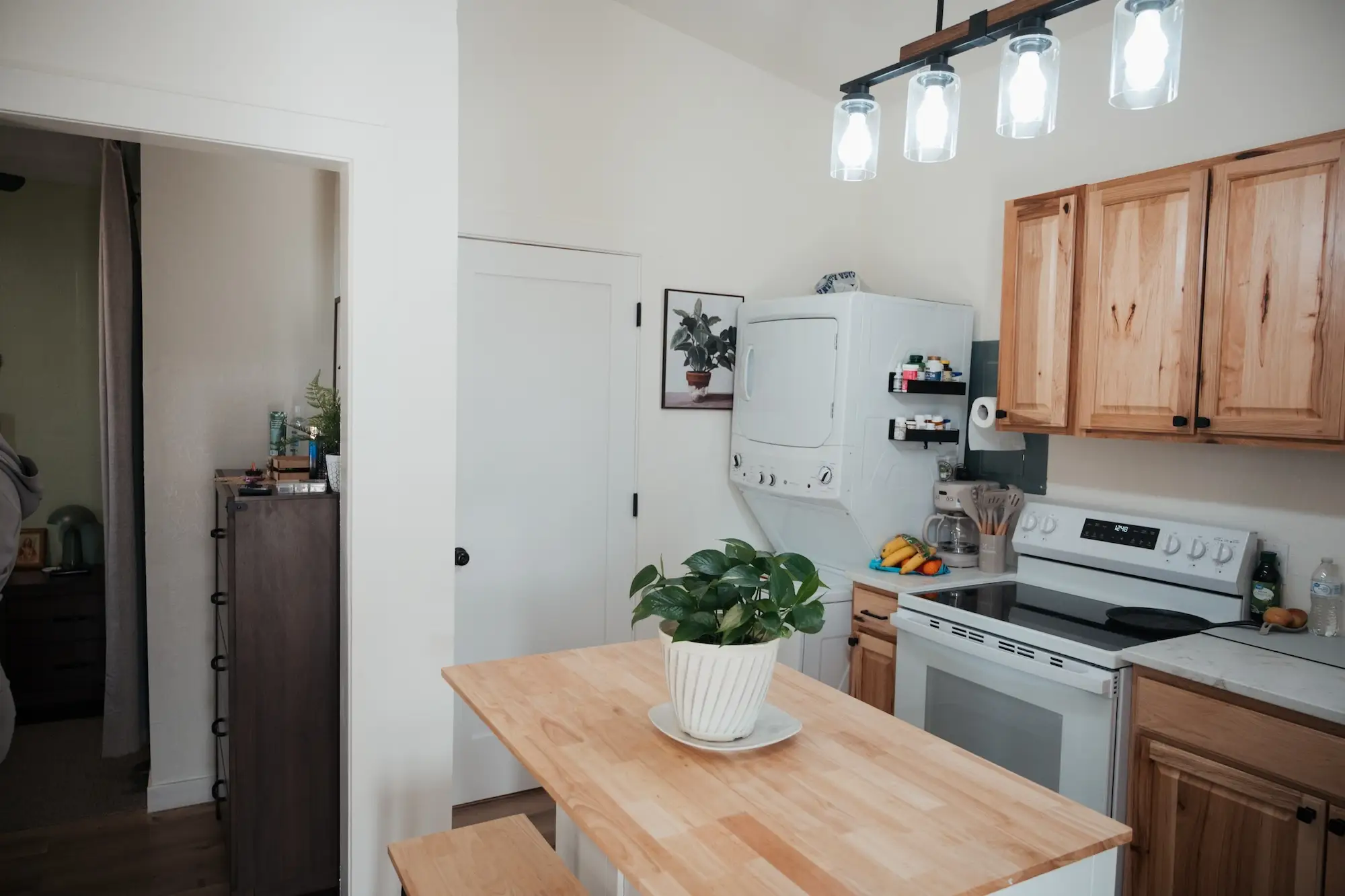 A kitchen with a wood island and cabinets. A washing machine sits in the far corner.