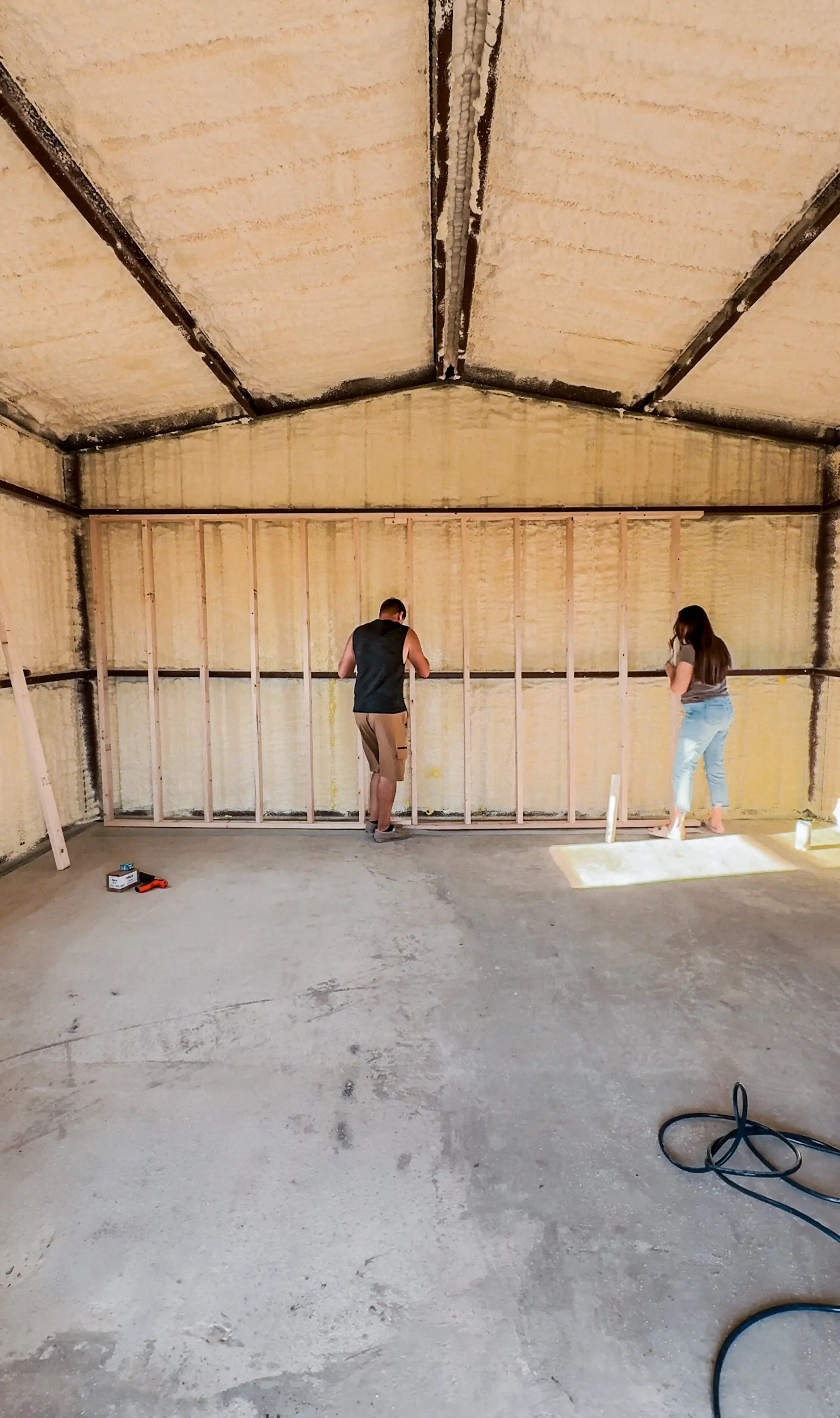 A couple puts up beams in a house that's being constructed.