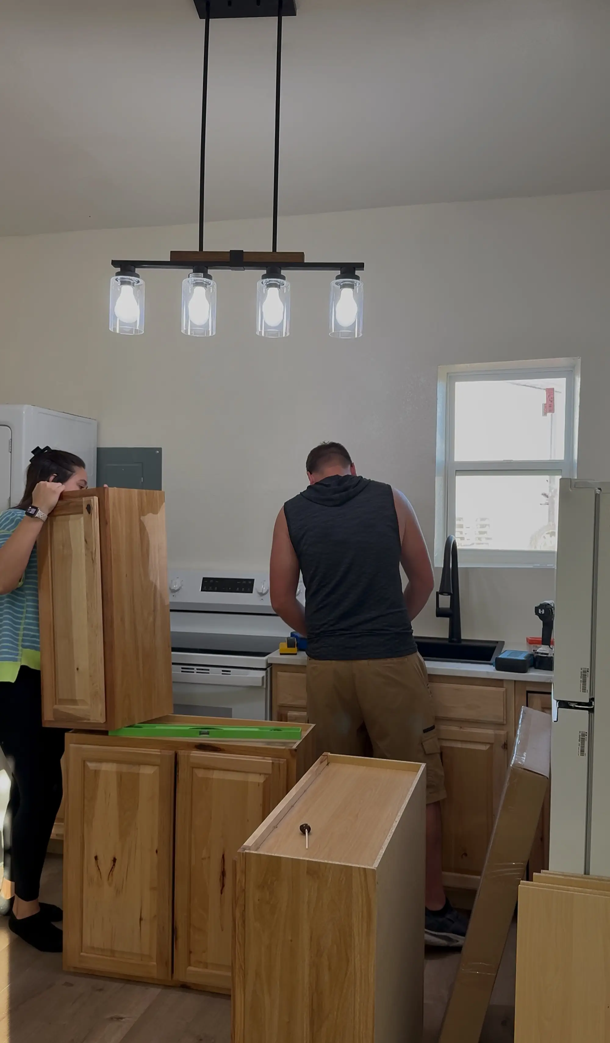 A couple puts up cabinets in a kitchen.