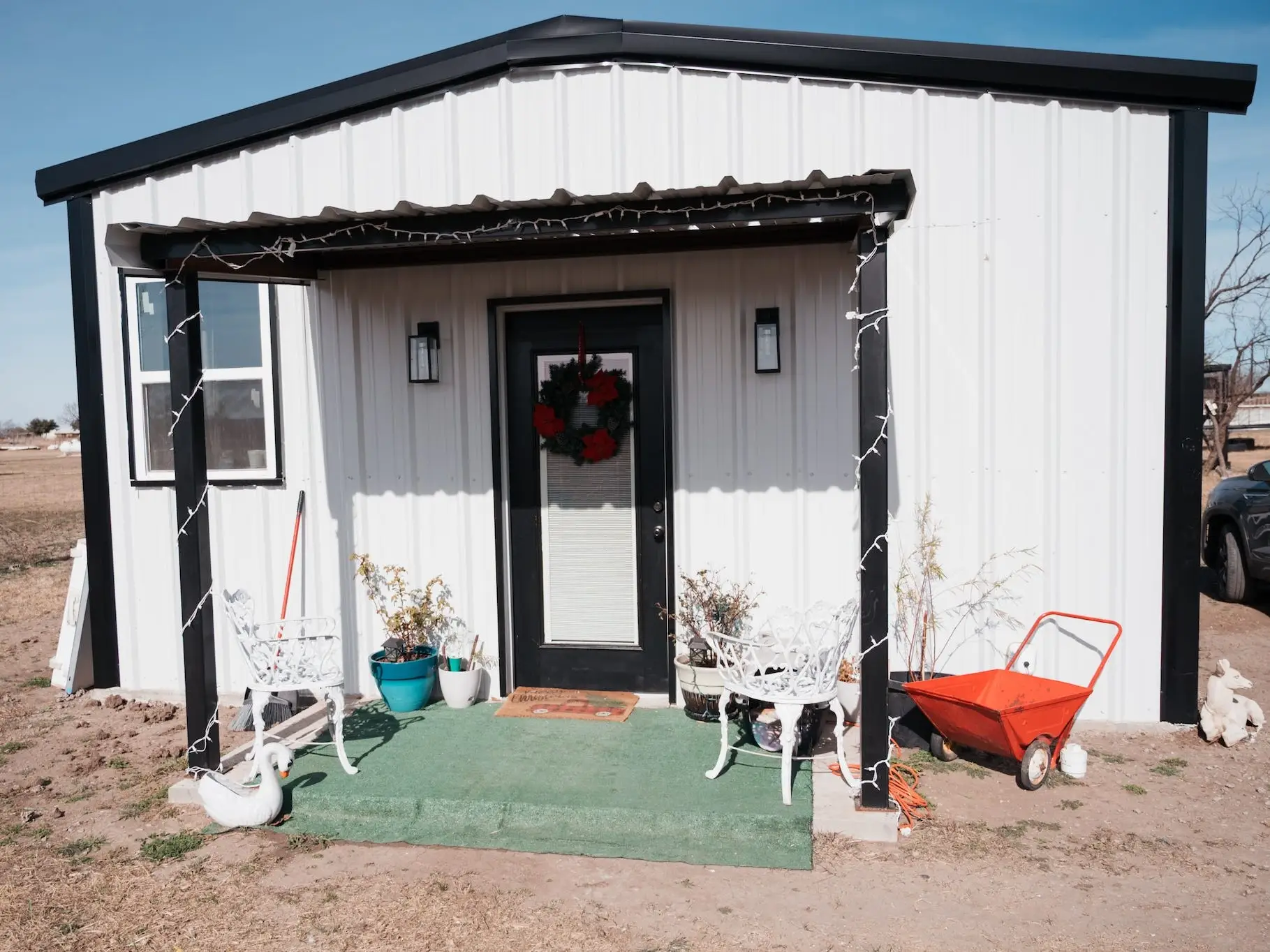 A white tiny home with a wreath on the front door.