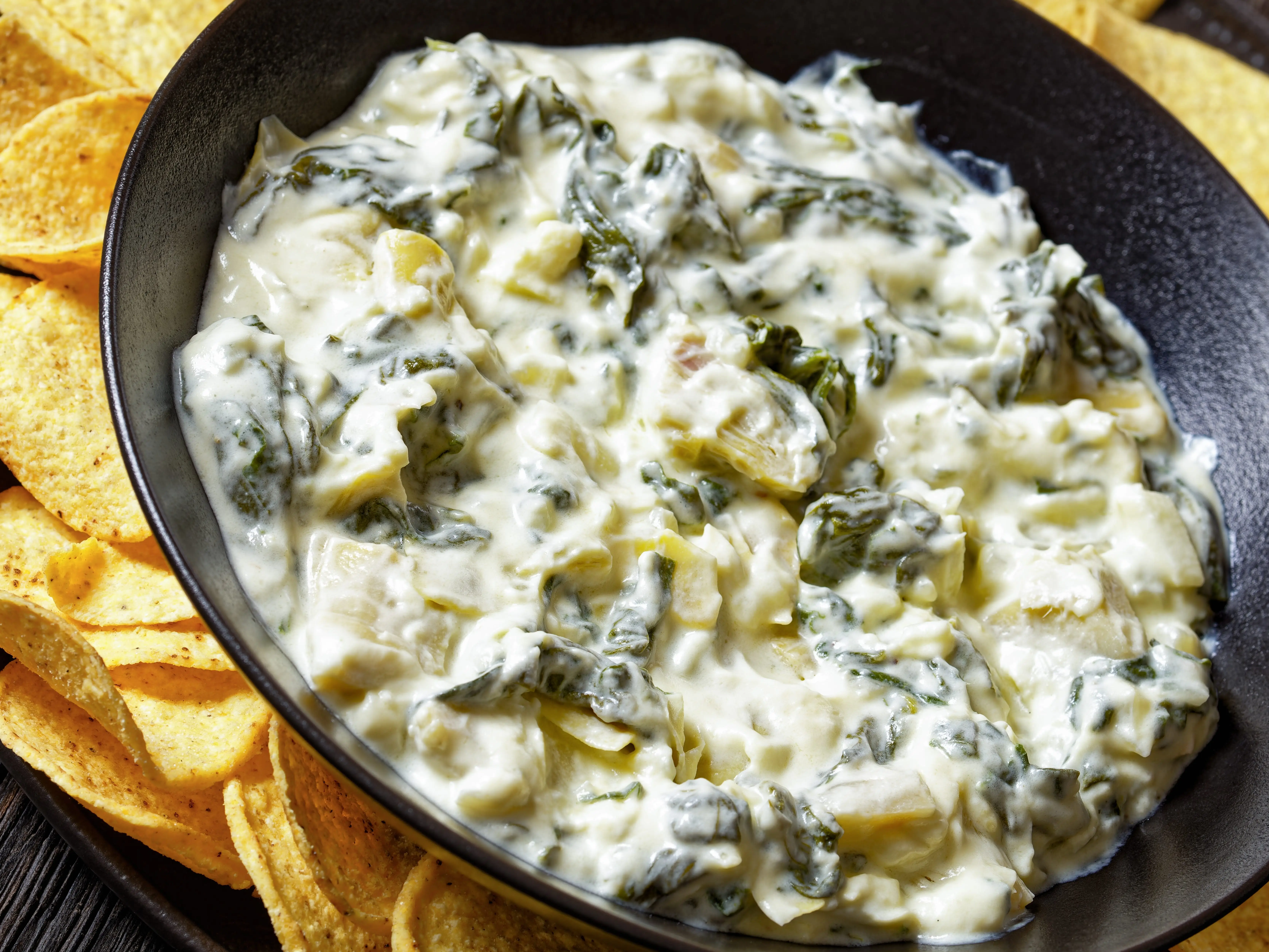 spinach and artichoke dip in a bowl with chips on the side