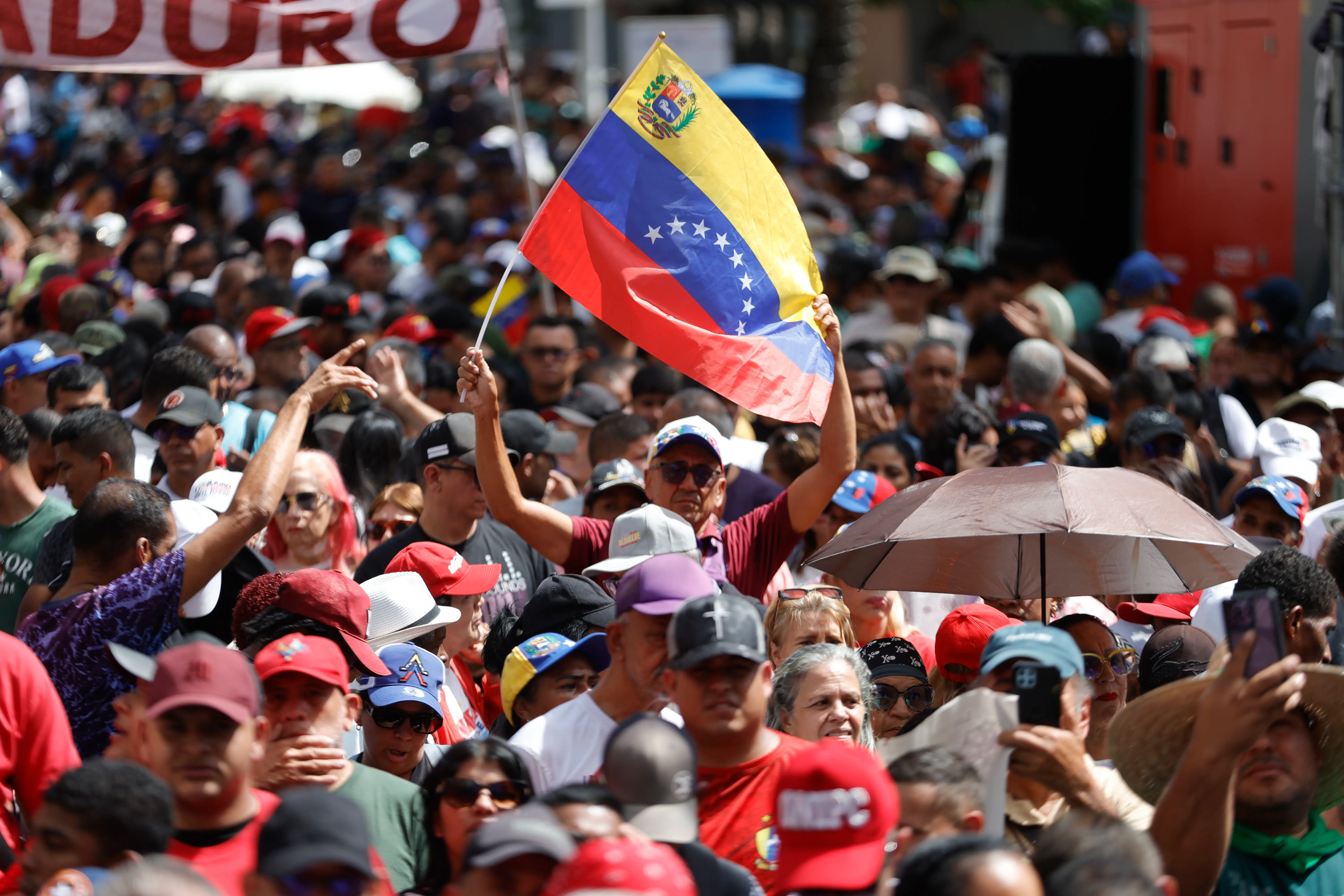 Crowds gather in the Caracas city center, one man holds a Venezuela flag.