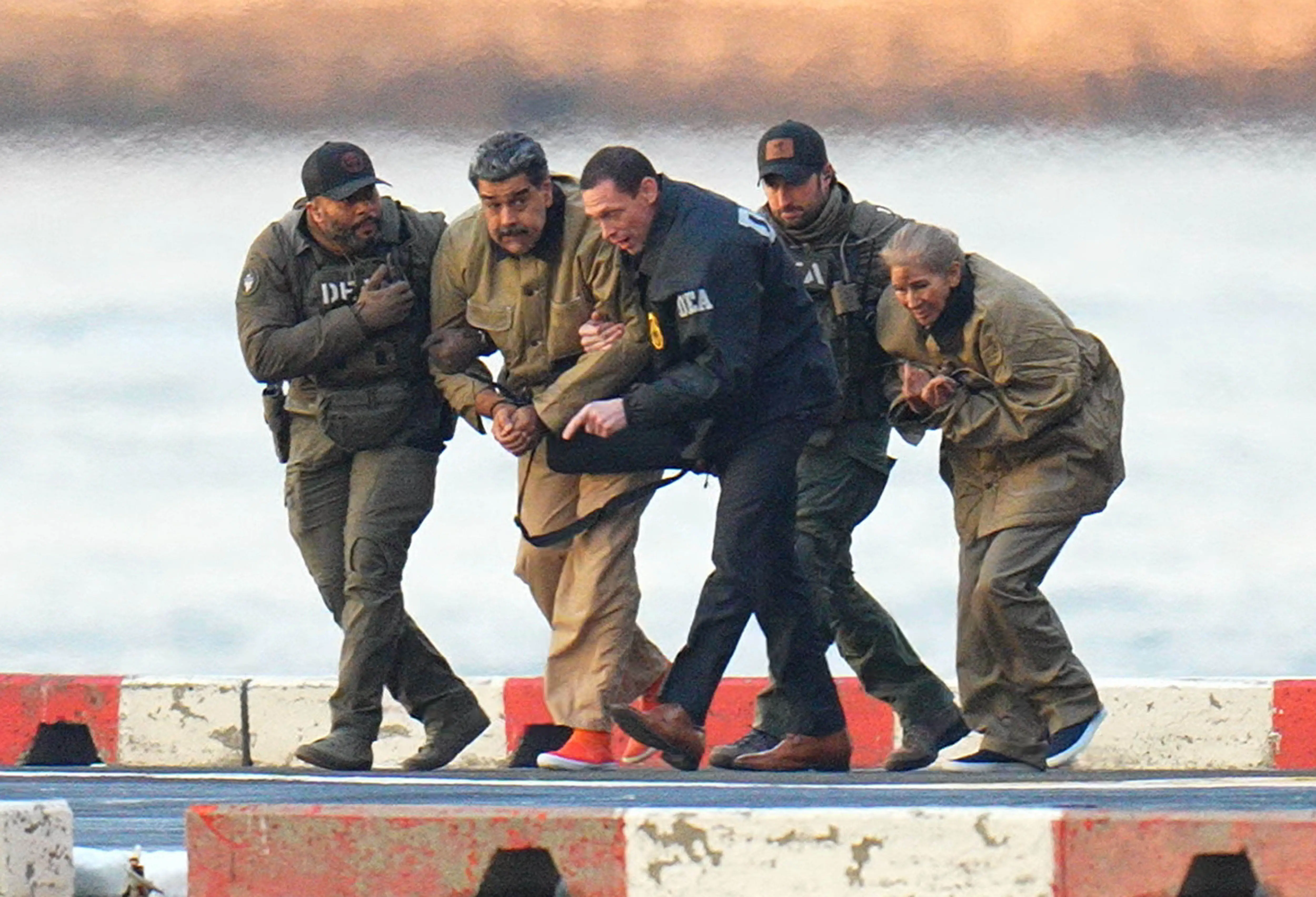 Nicolas Maduro and his wife, Cilia Flores, are seen in handcuffs after landing at a Manhattan helipad, escorted by heavily armed federak agents.