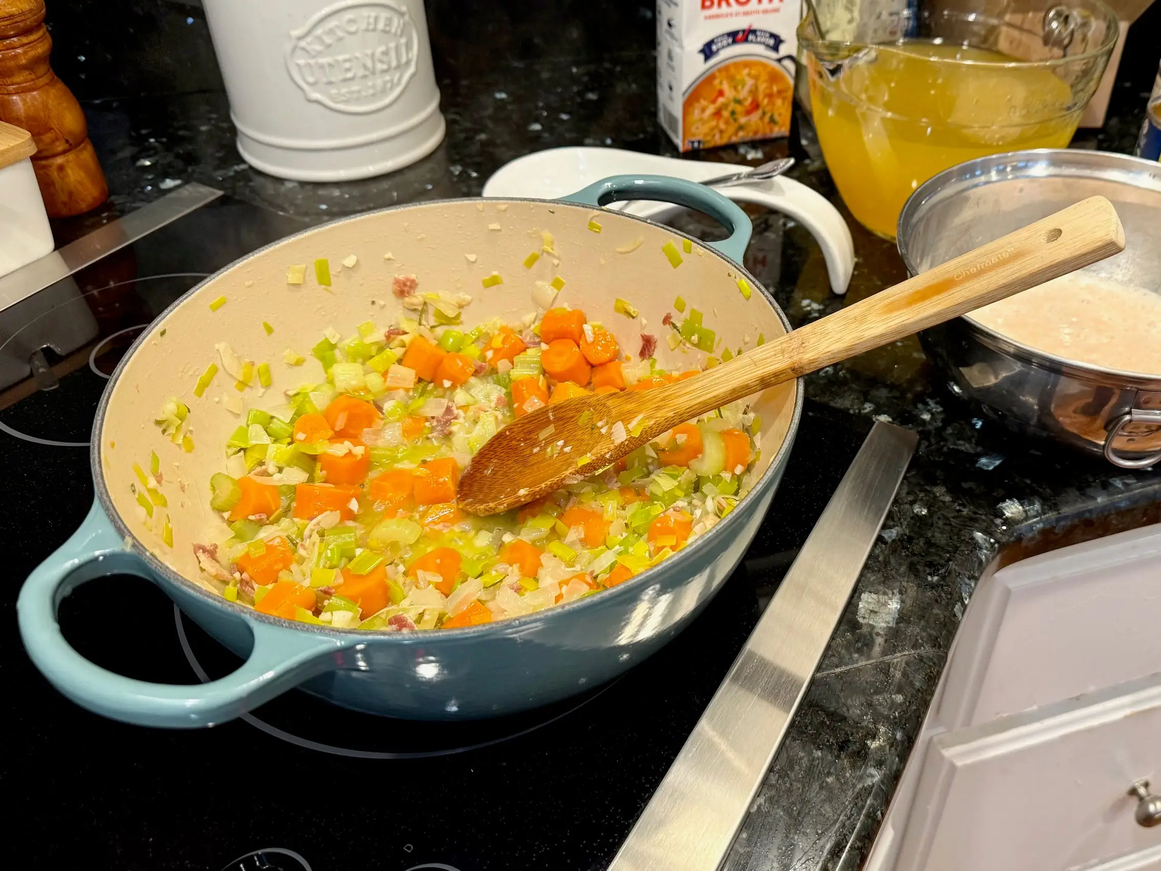 A pot full of chopped vegetables on a stove with a wooden spoon.