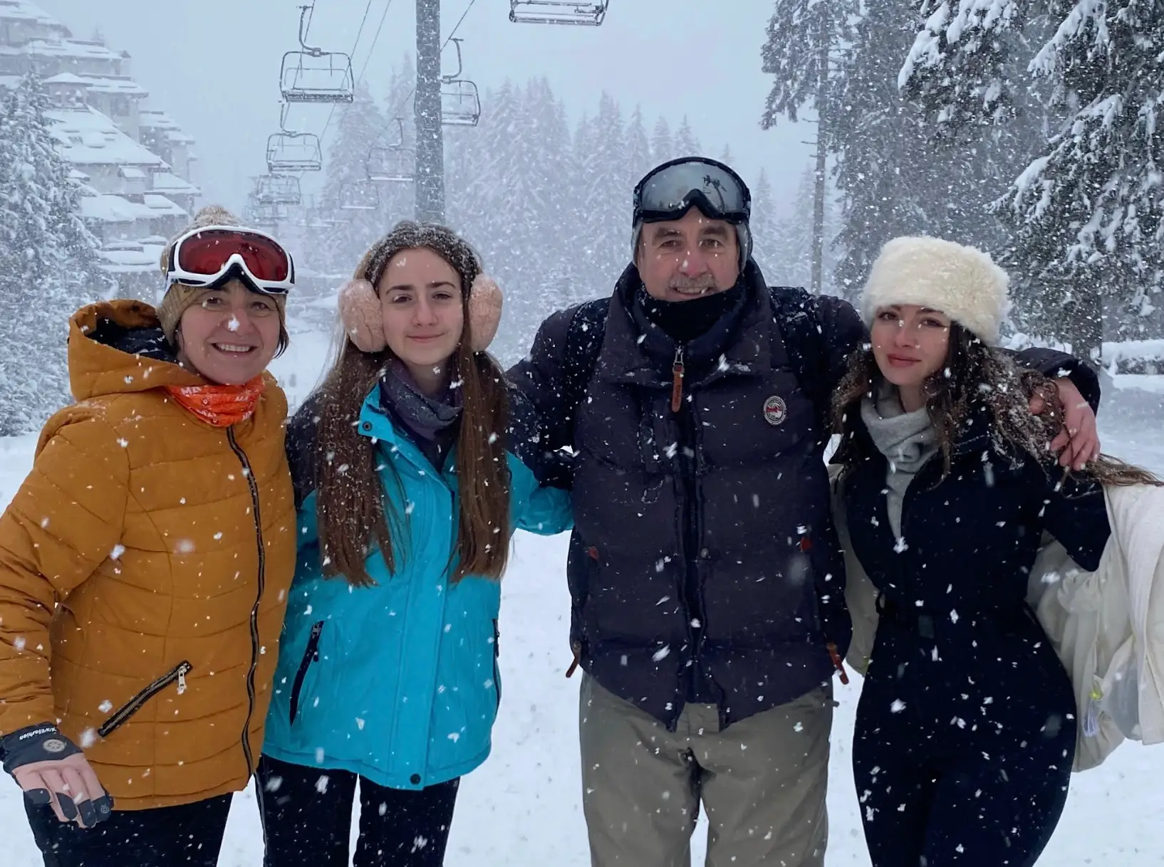 The writer and her family standing close together near ski lifts, wearing snow gear.