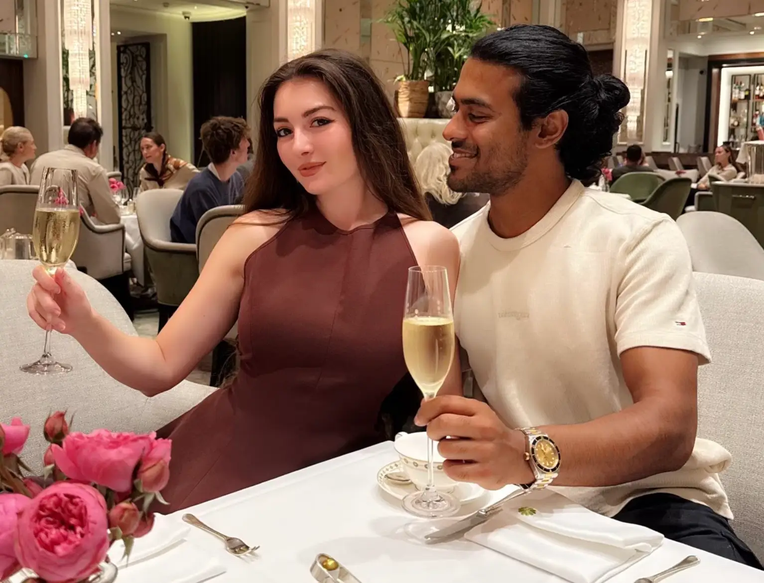 The writer and her partner holding up glasses of champagne at a restaurant.