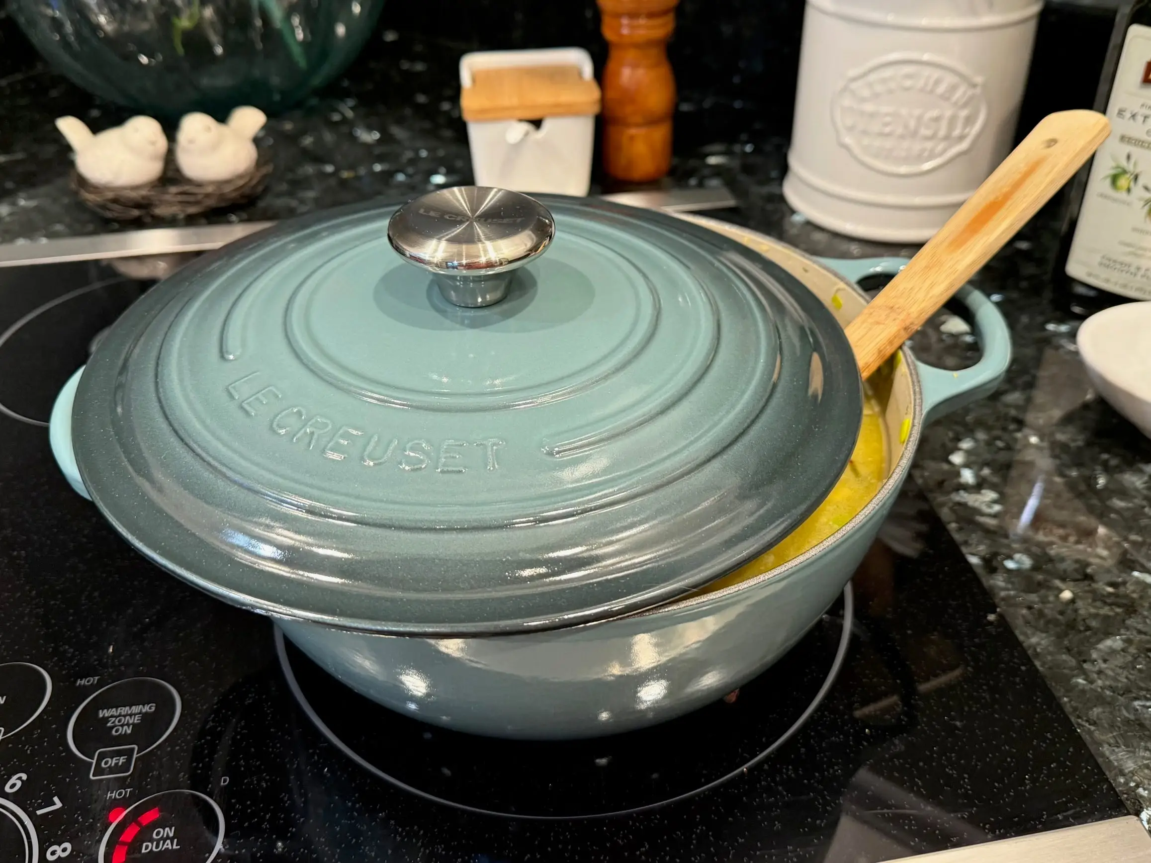 A pot of soup partially uncovered on a stove.