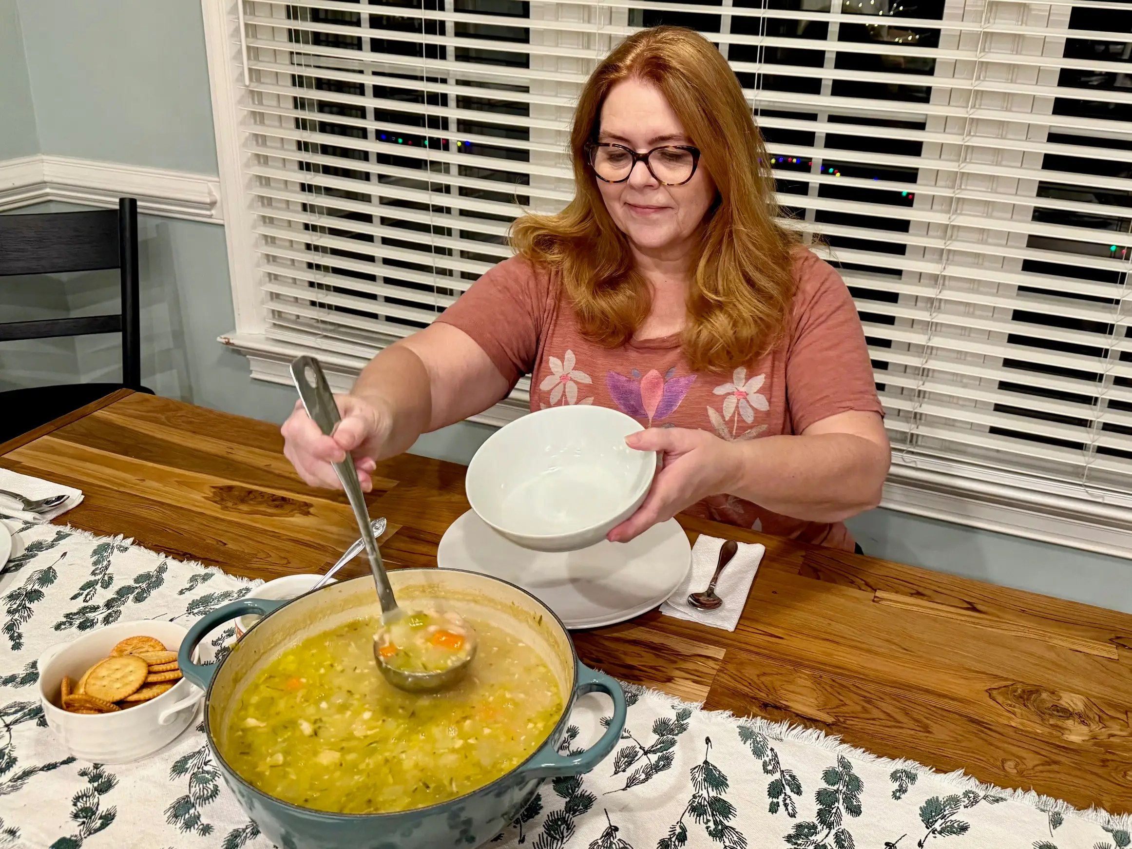 Kristina uses a ladle to scoop soup into a white bowl.