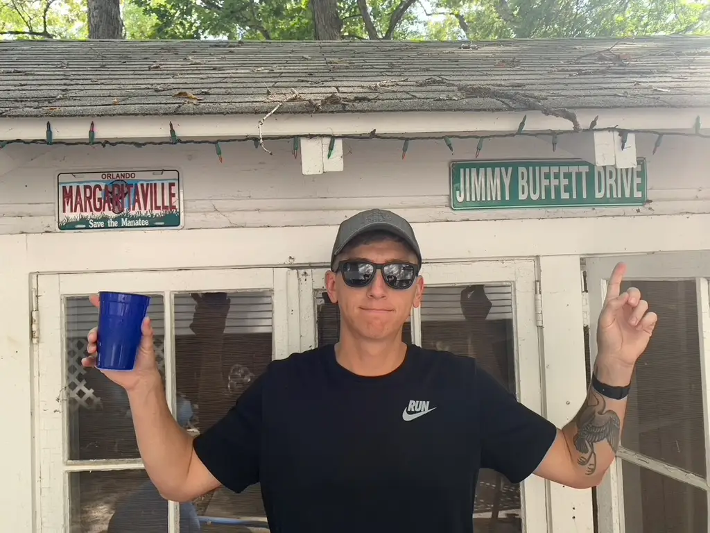 Author pointing to signs on side of house